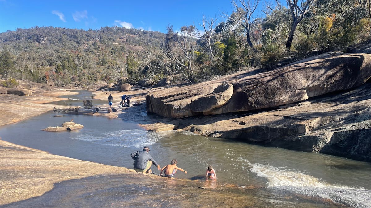 people by a creek cut through the rocks