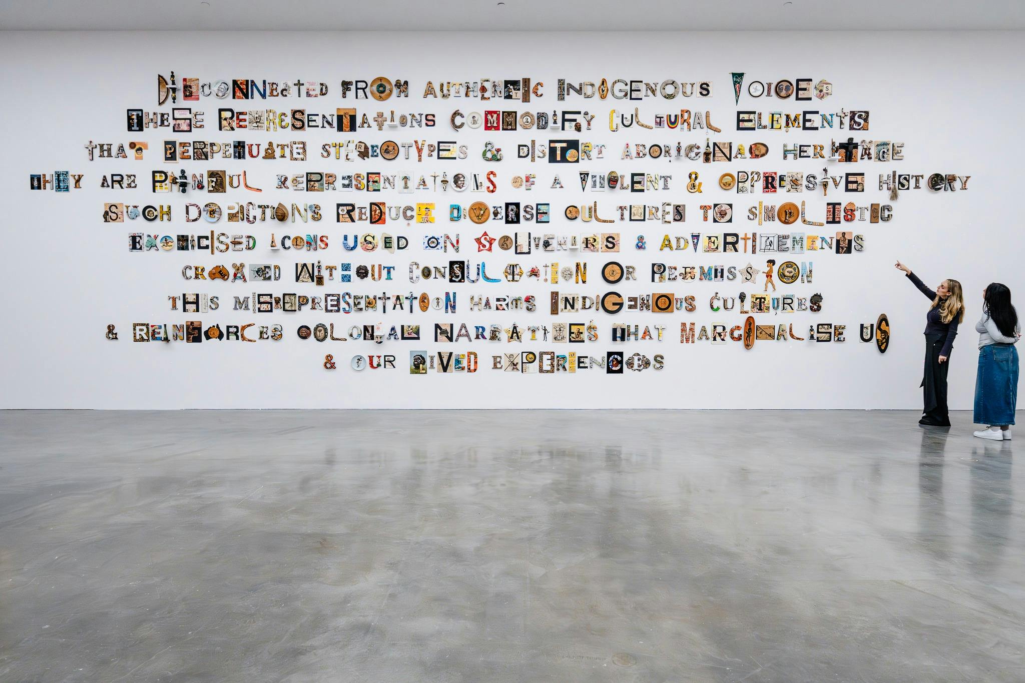Text-based artwork fills a large gallery wall for Tony Albert's artwork, Disconnected.