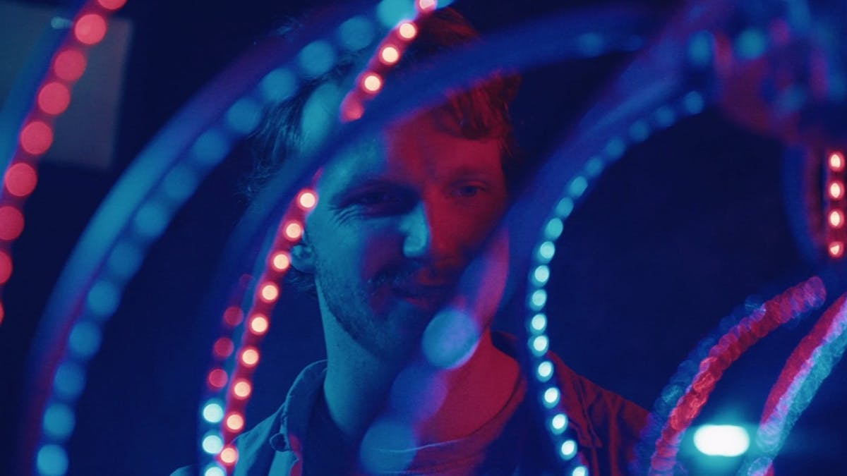 The foreground is filled with spiraling glowing tentacles.  A face is looking through them