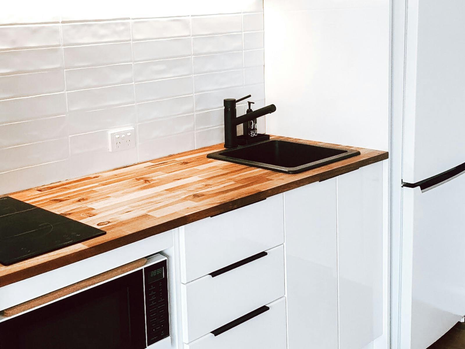 View of wooden bench top in kitchen with electric stove, microwave and refrigerator