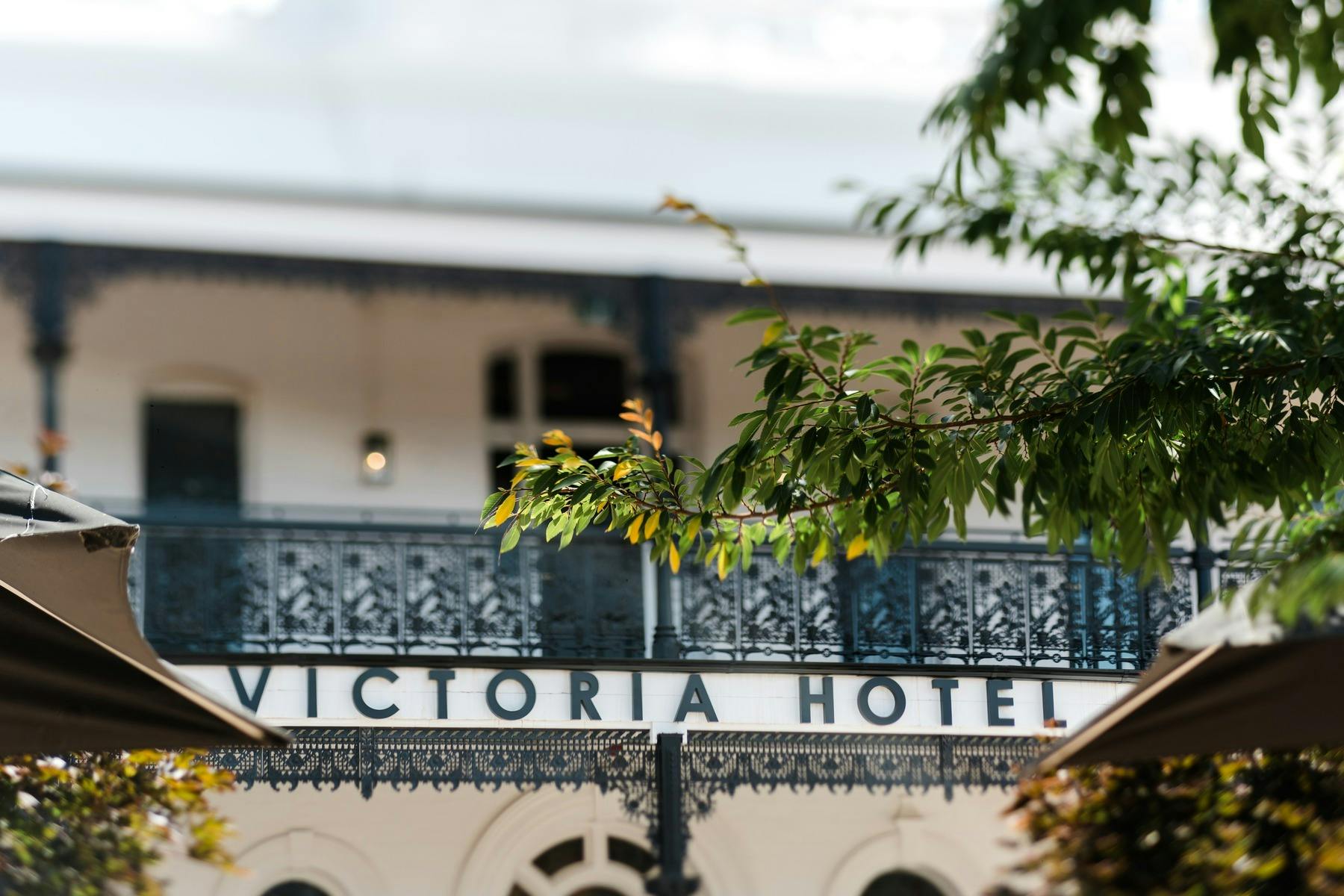 Facade of the Victoria Hotel. White building with black lattice on balcony