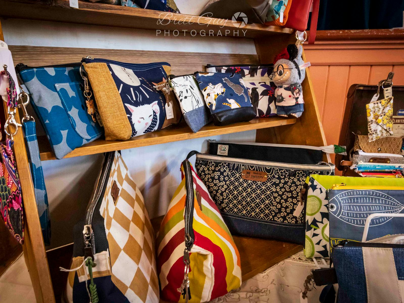 various coloured handbags and purses displayed on shelves