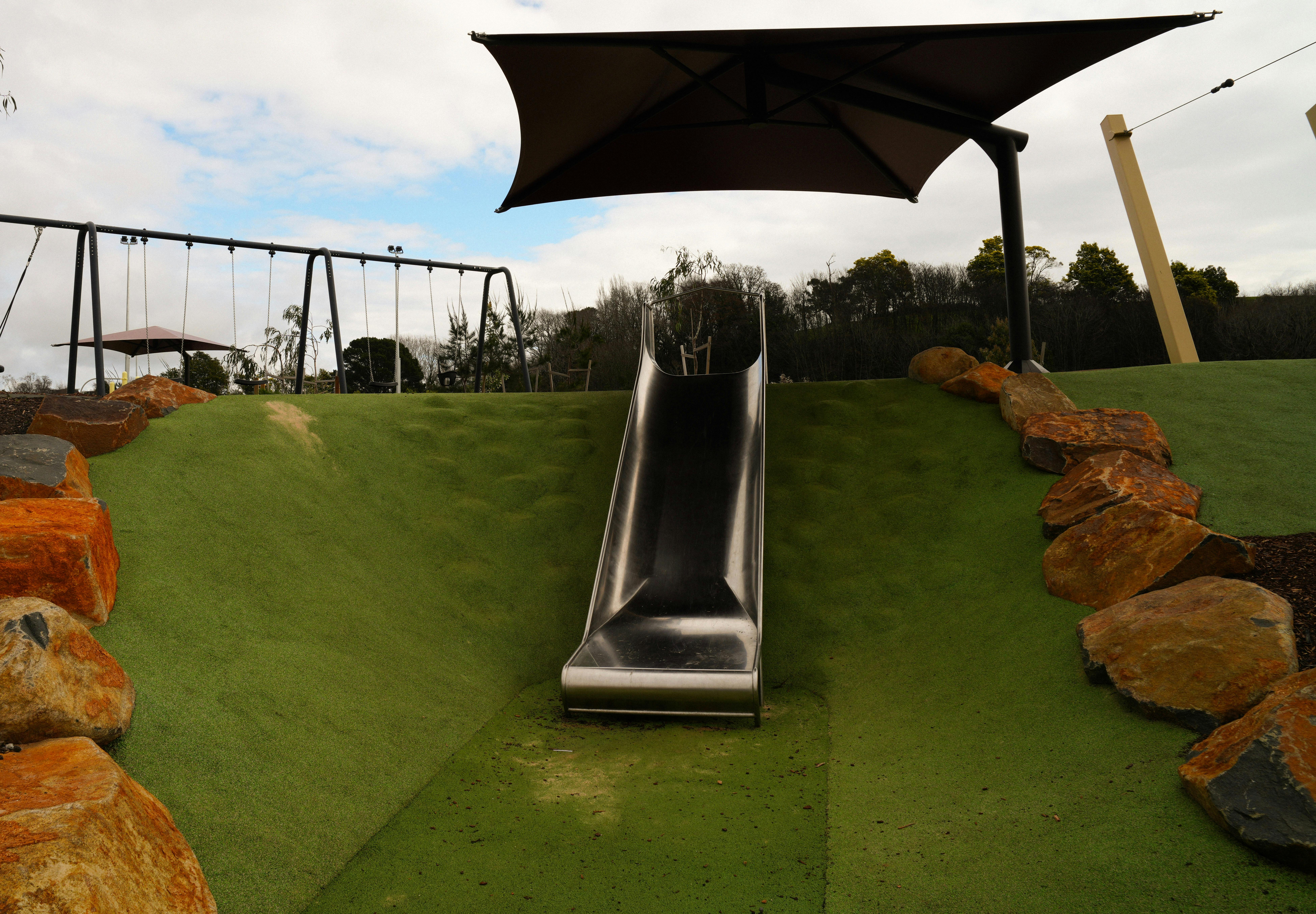 A slippery slide with swings in the back ground