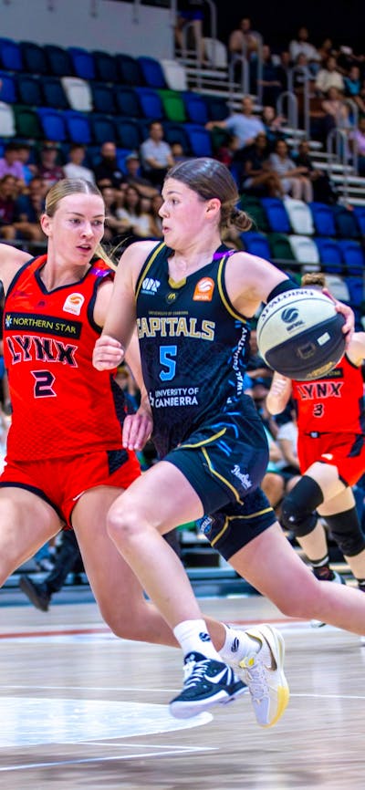 UC Capitals player driving to the basket for a layup during a WNBL game against Perth Lynx.