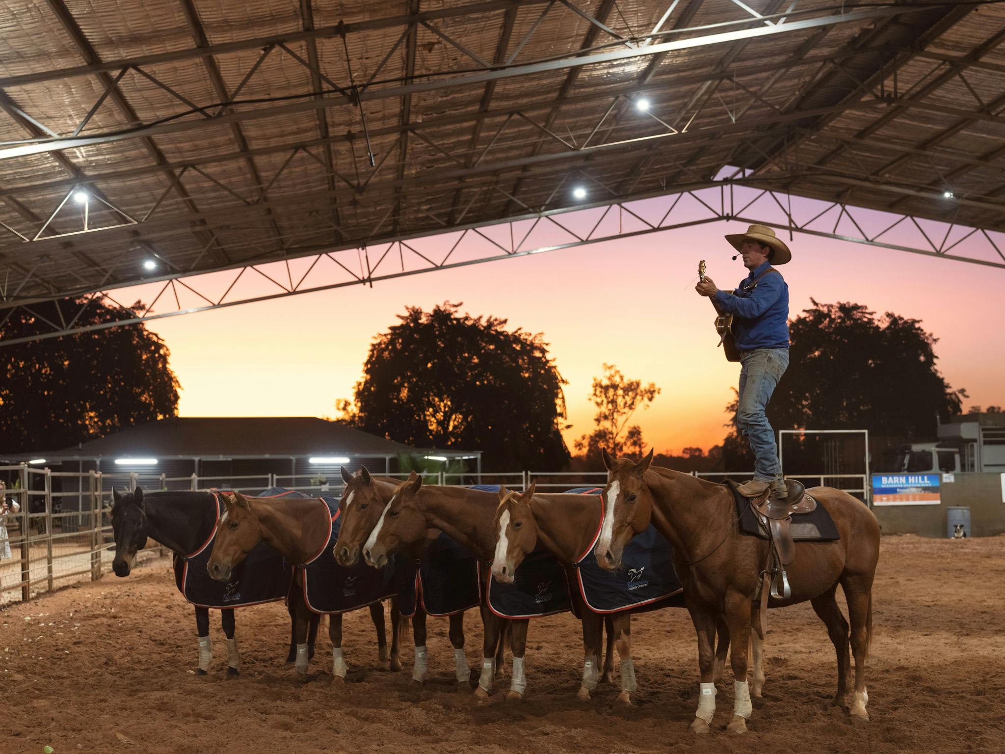 Man stands on the back of a horse.