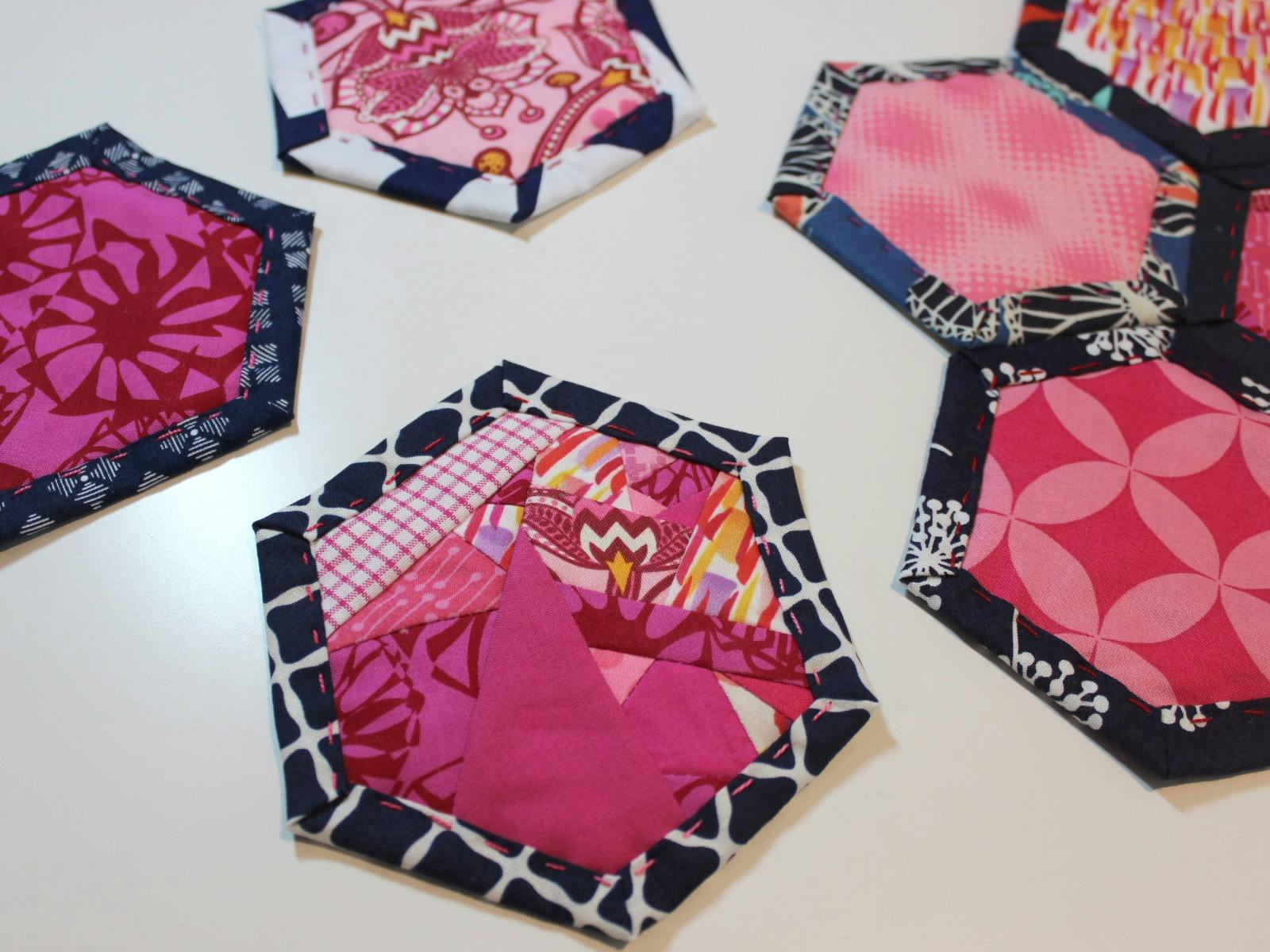 Pink patterned fabric is surrounded by blue fabric to create a hexagon