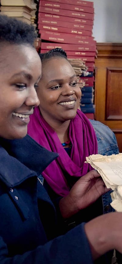 Two women reading books in a room full of books and manuscripts