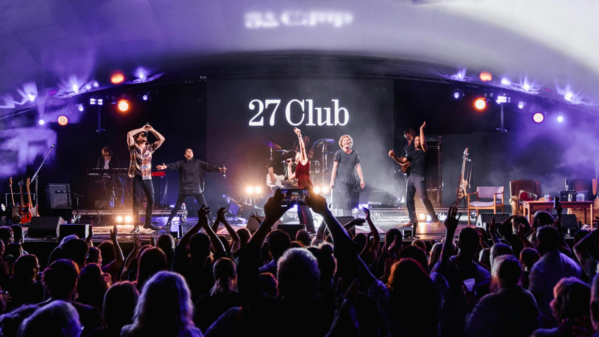 27 Club - 4 singers on stage performing in front of a crowd