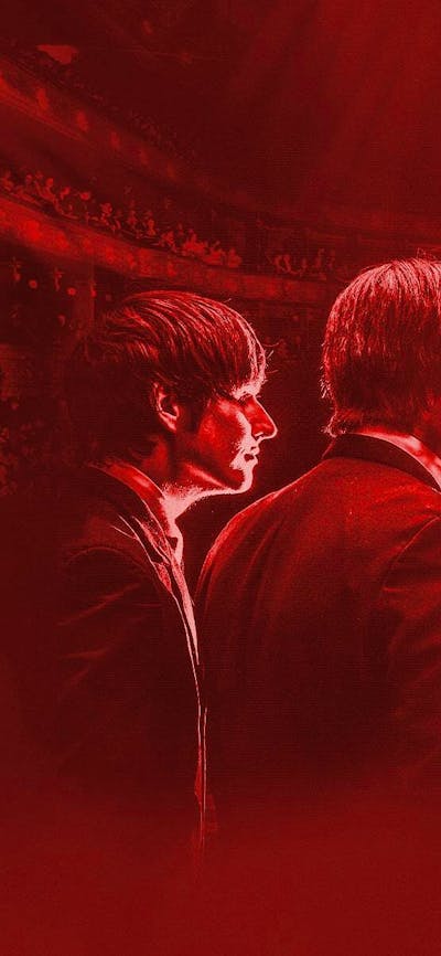 Four men with their backs to the camera stand in a red haze looking out