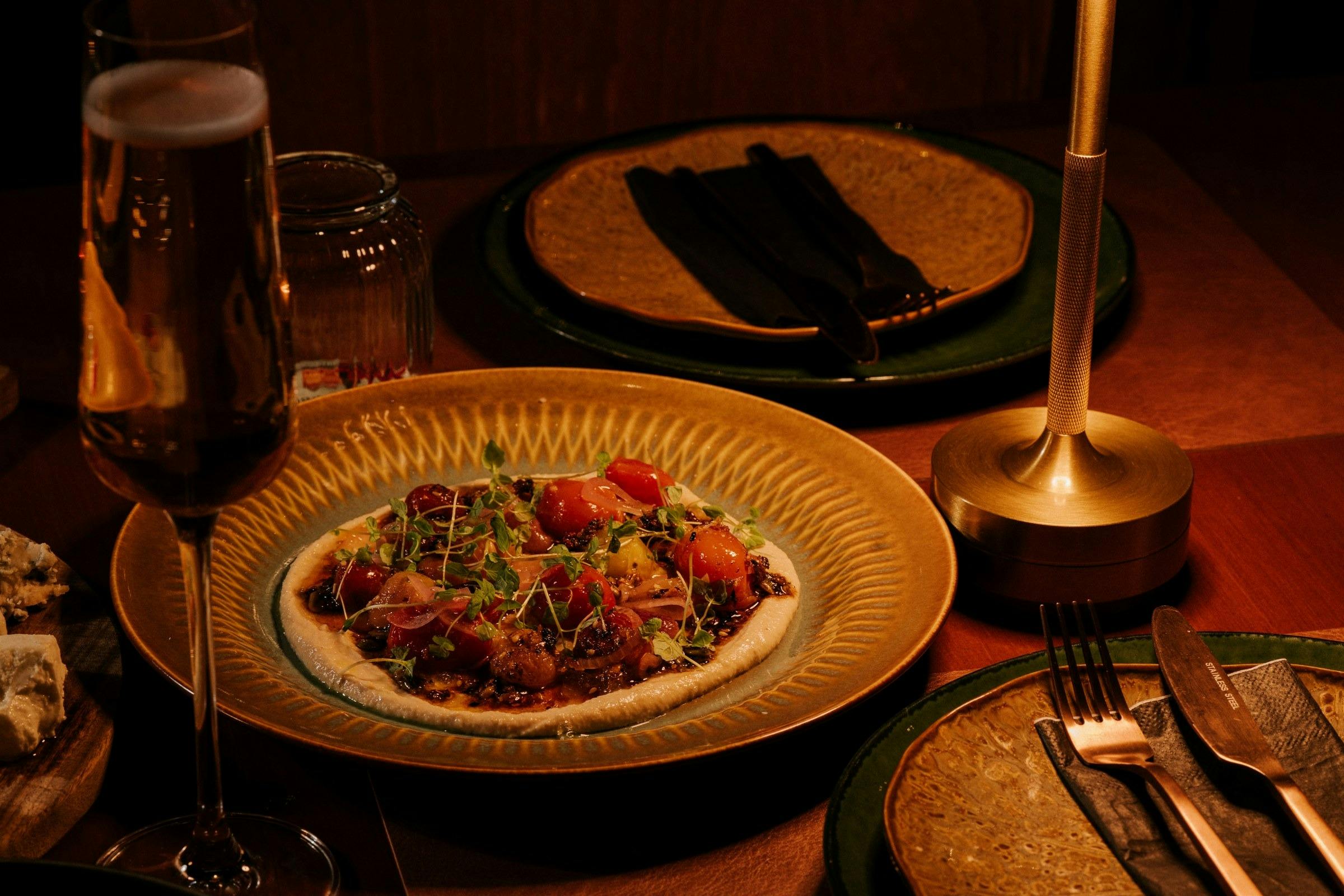 Plated heirloom tomato dish on a gold plate with a glass of sparkling wine