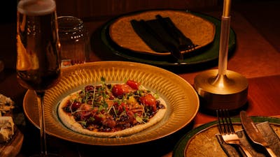 Plated heirloom tomato dish on a gold plate with a glass of sparkling wine