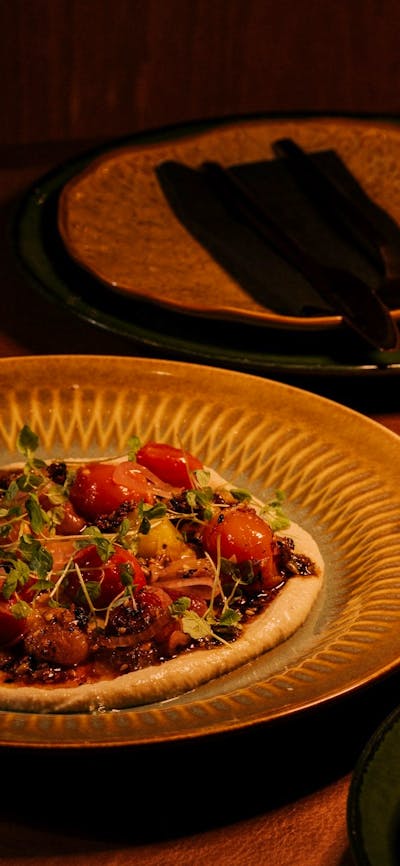 Plated heirloom tomato dish on a gold plate with a glass of sparkling wine