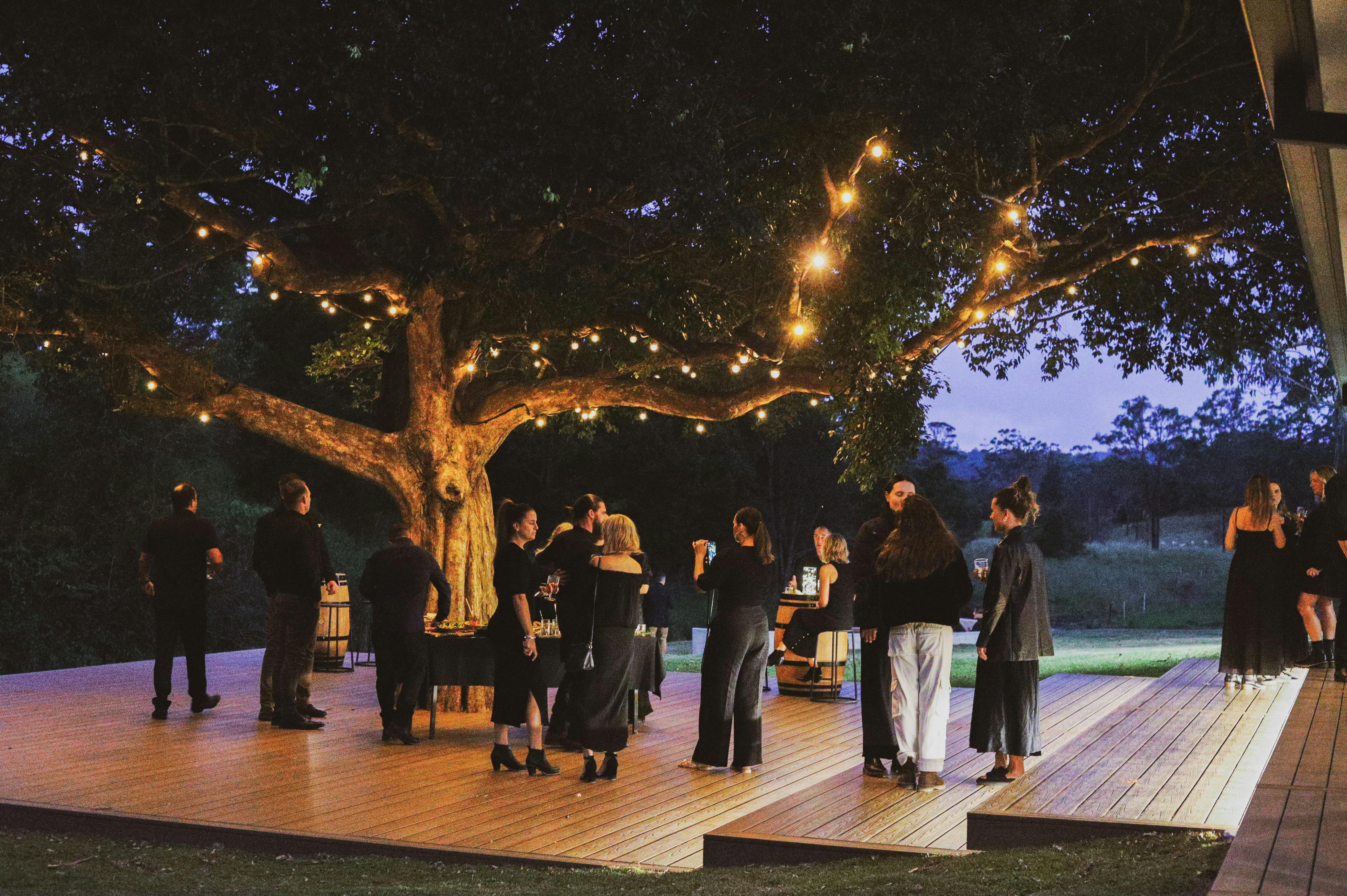 갑판 위에 나무와 화환 조명이 있는 검은색 옷을 입은 사람들