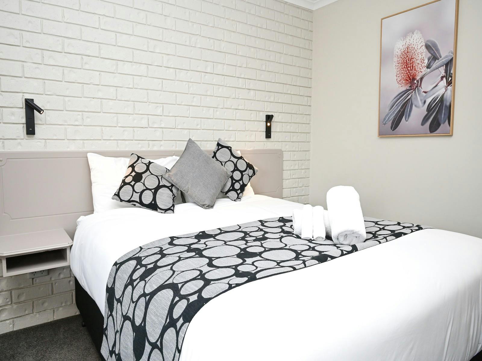 White walled room, double bed with grey pillows