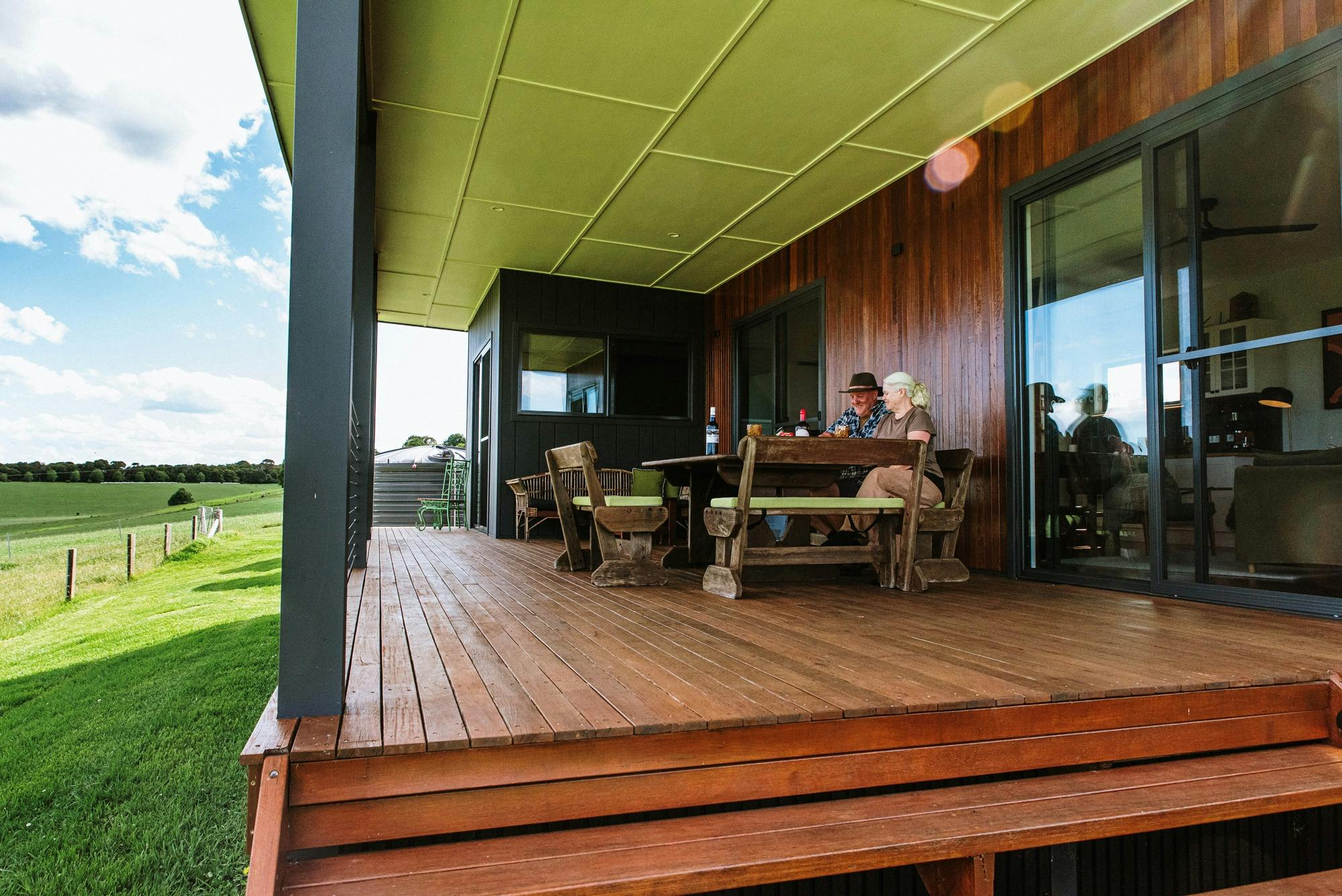 Photo of long outside deck with table and a woman and a man enjoying wine and cheese