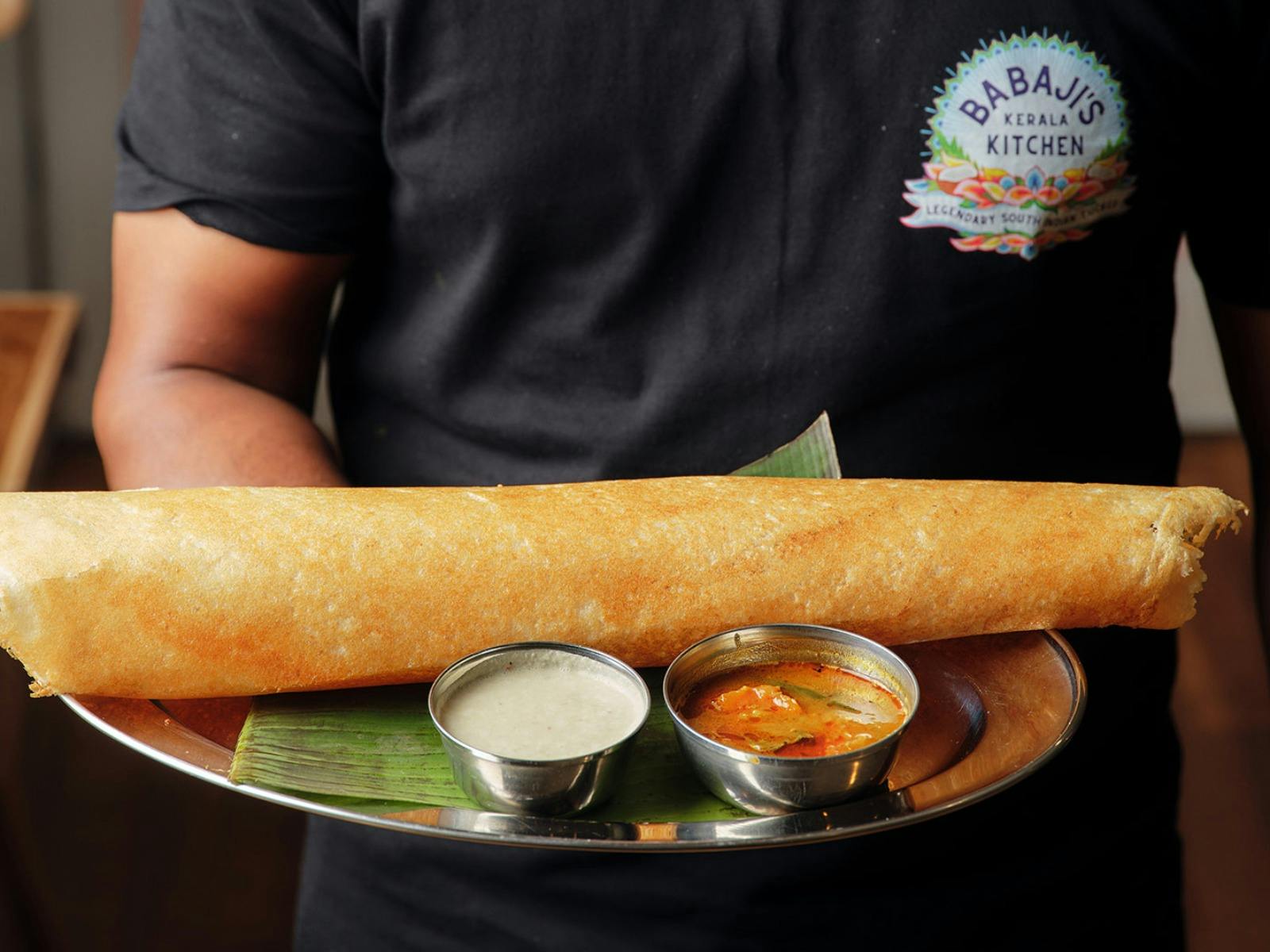 A crispy dosa sits on banana leaf