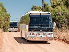 Picture of a bus driving down a  dirt road
