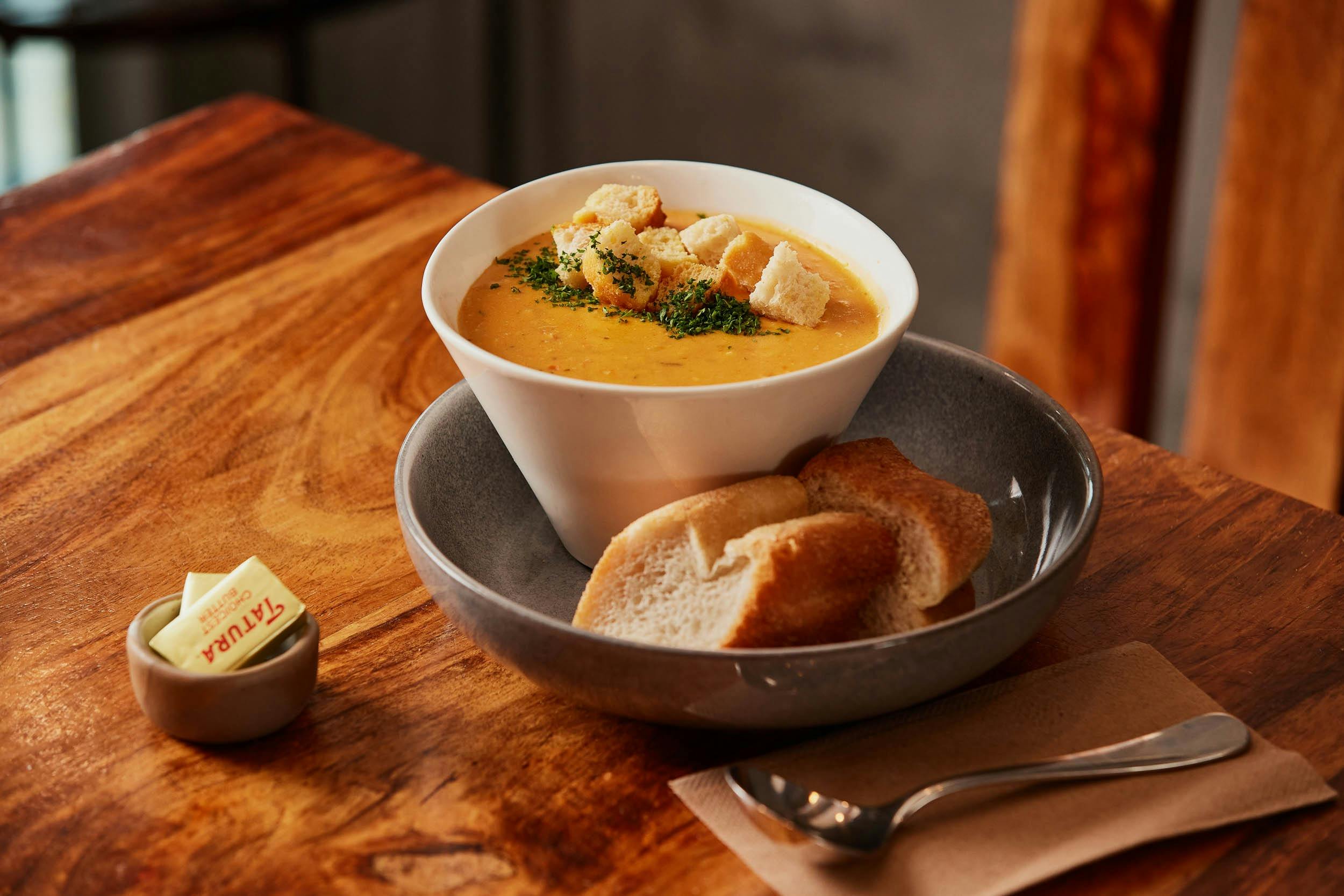 A bowl of seafood chowder served with bread and butter
