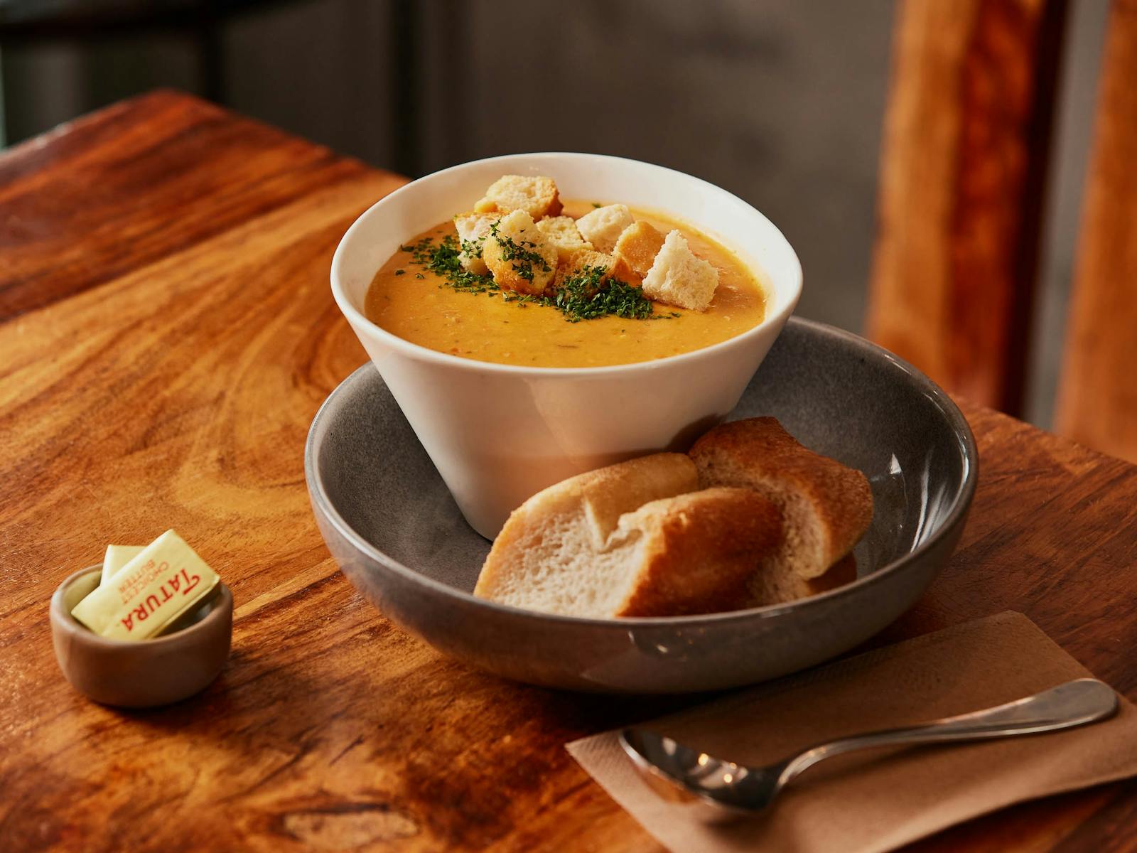 A bowl of seafood chowder served with bread and butter