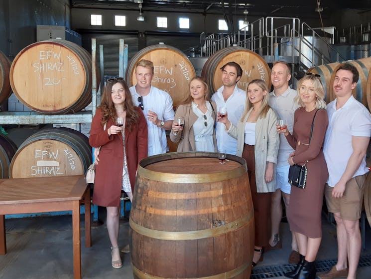 Group of friends in front of wine barrels on a Kenny Escapes Wine Tasting Tour