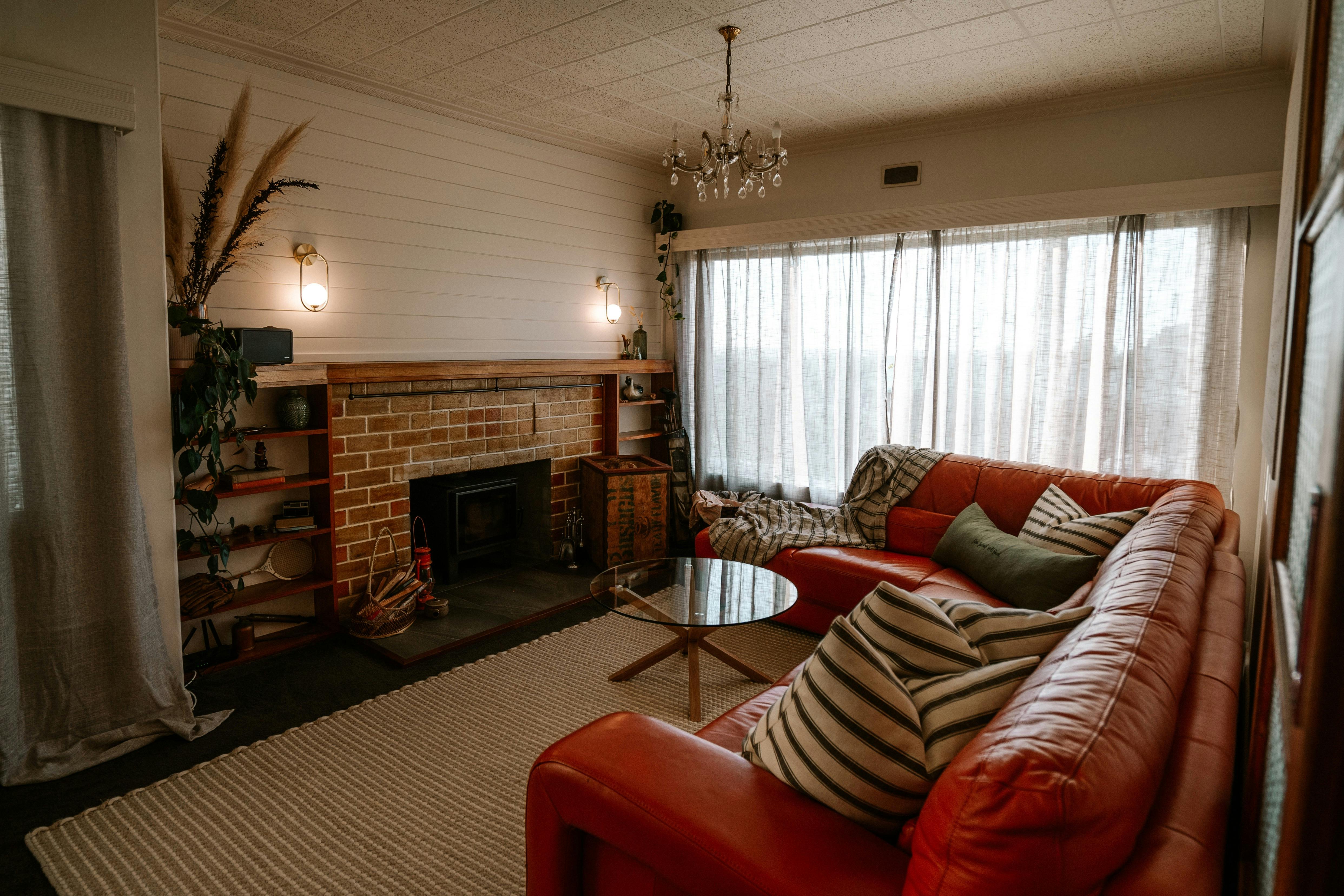Large orange leather lounge suite with coffee table and wood burning fireplace