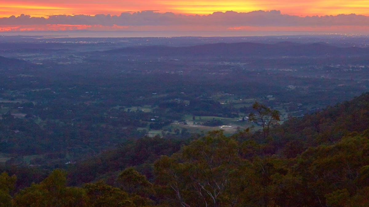View over a valley towards a sunset causing pink and orange hues in the sky