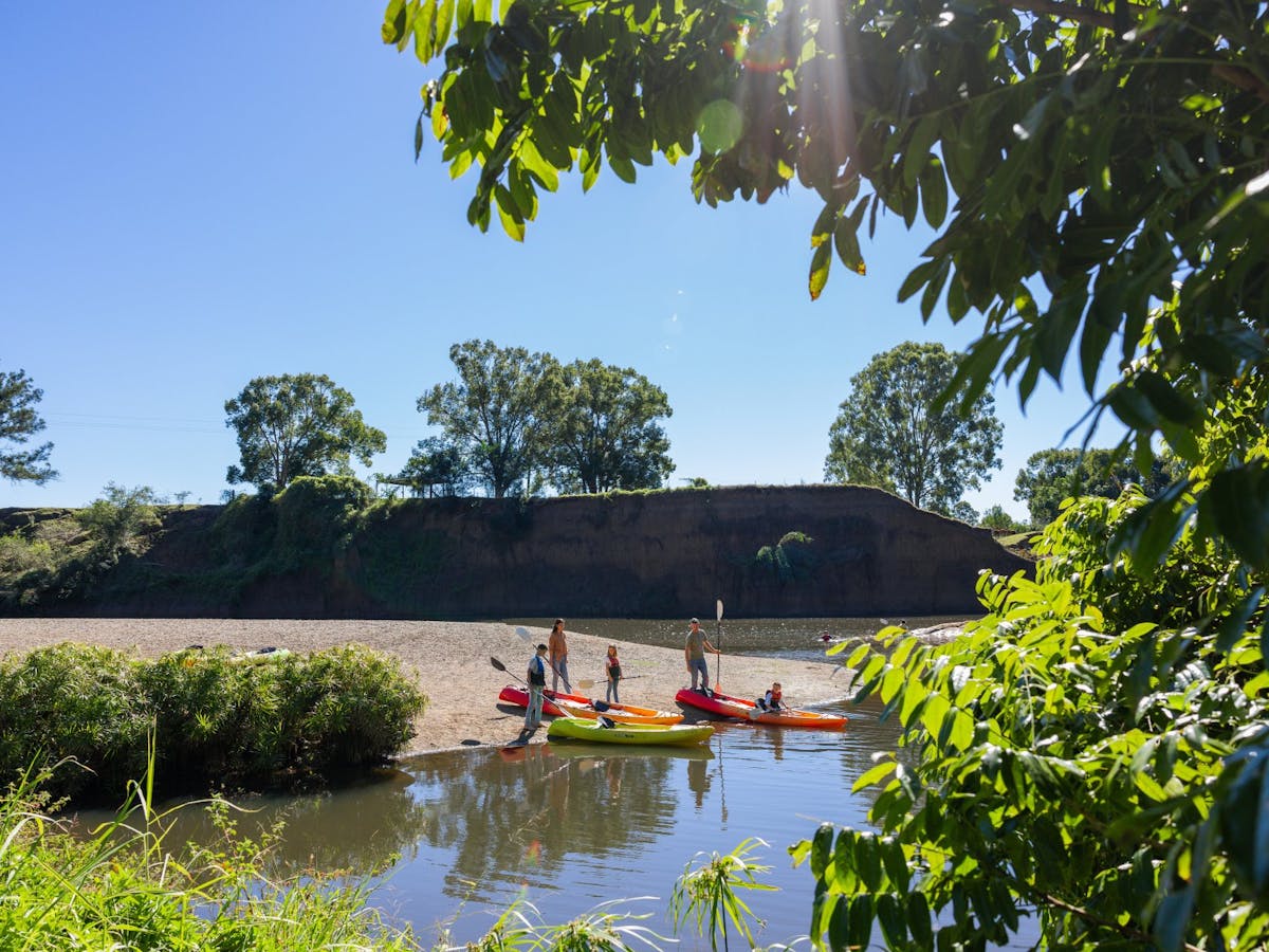 A family launching from the bank into the water