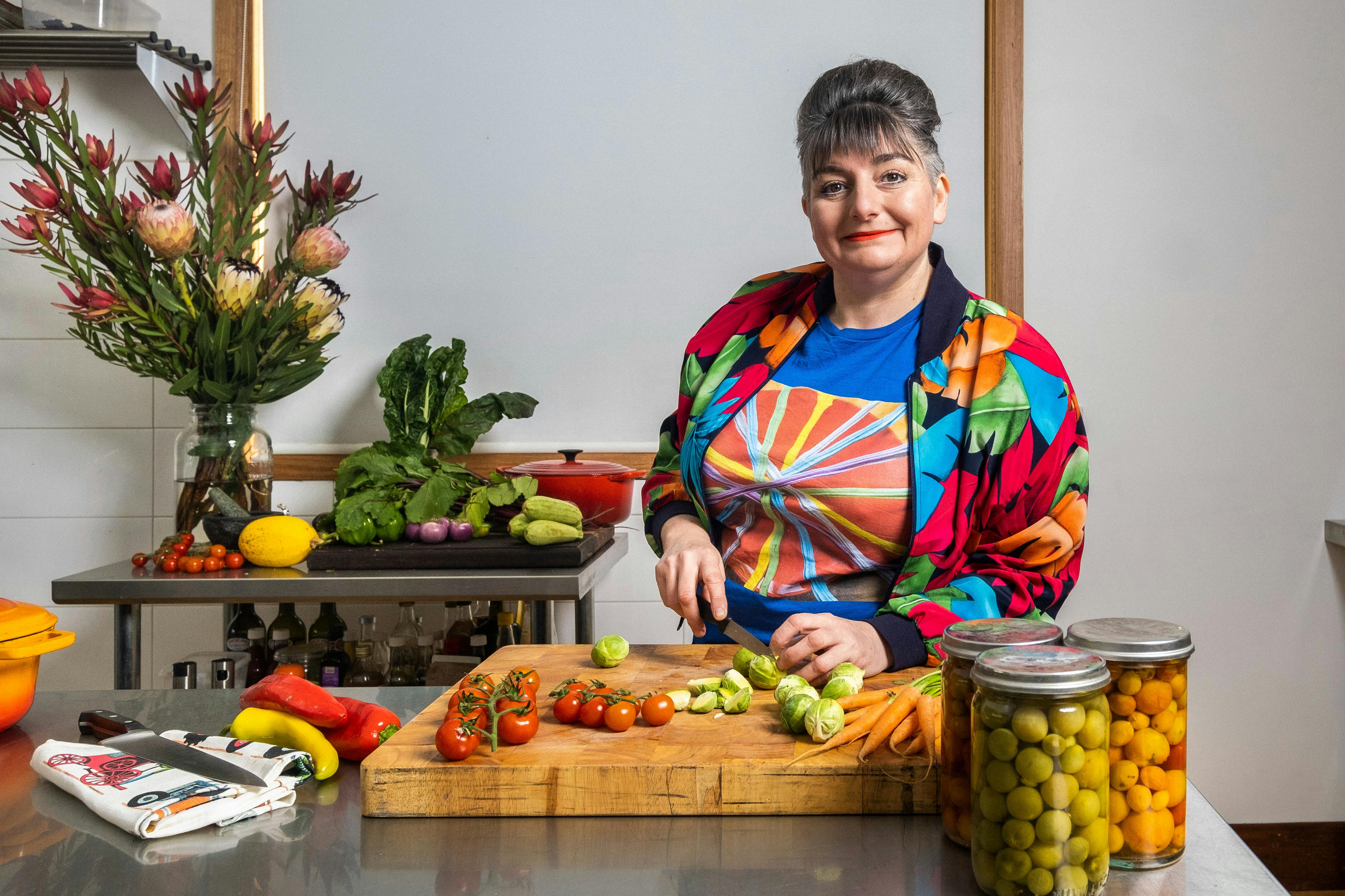 Chef in bright coloured cloths cutting up vegetables