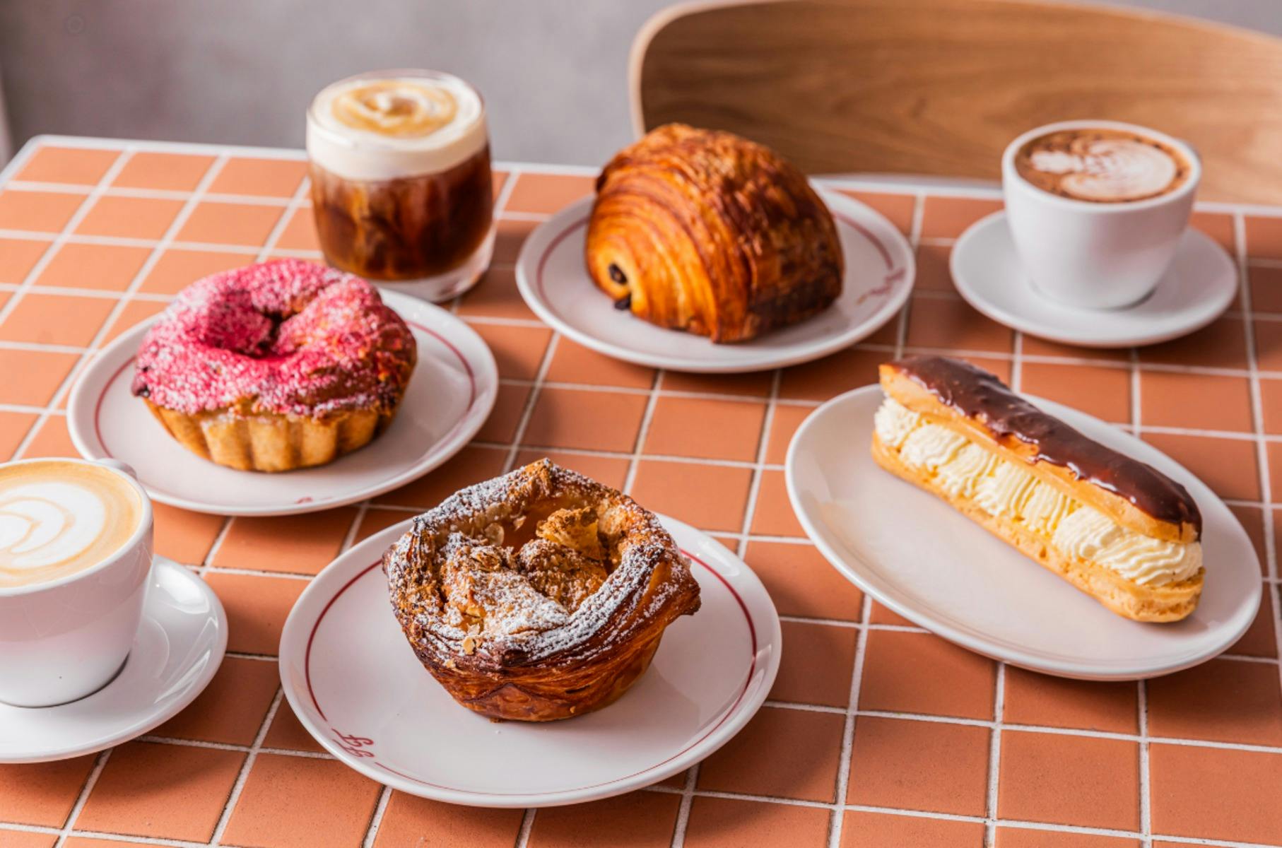 복숭아색 타일 테이블 위에 다양한 페이스트리가 놓여 있습니다.