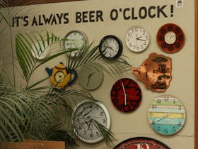 Wall with many clocks and a saying It's always beer o'clock!