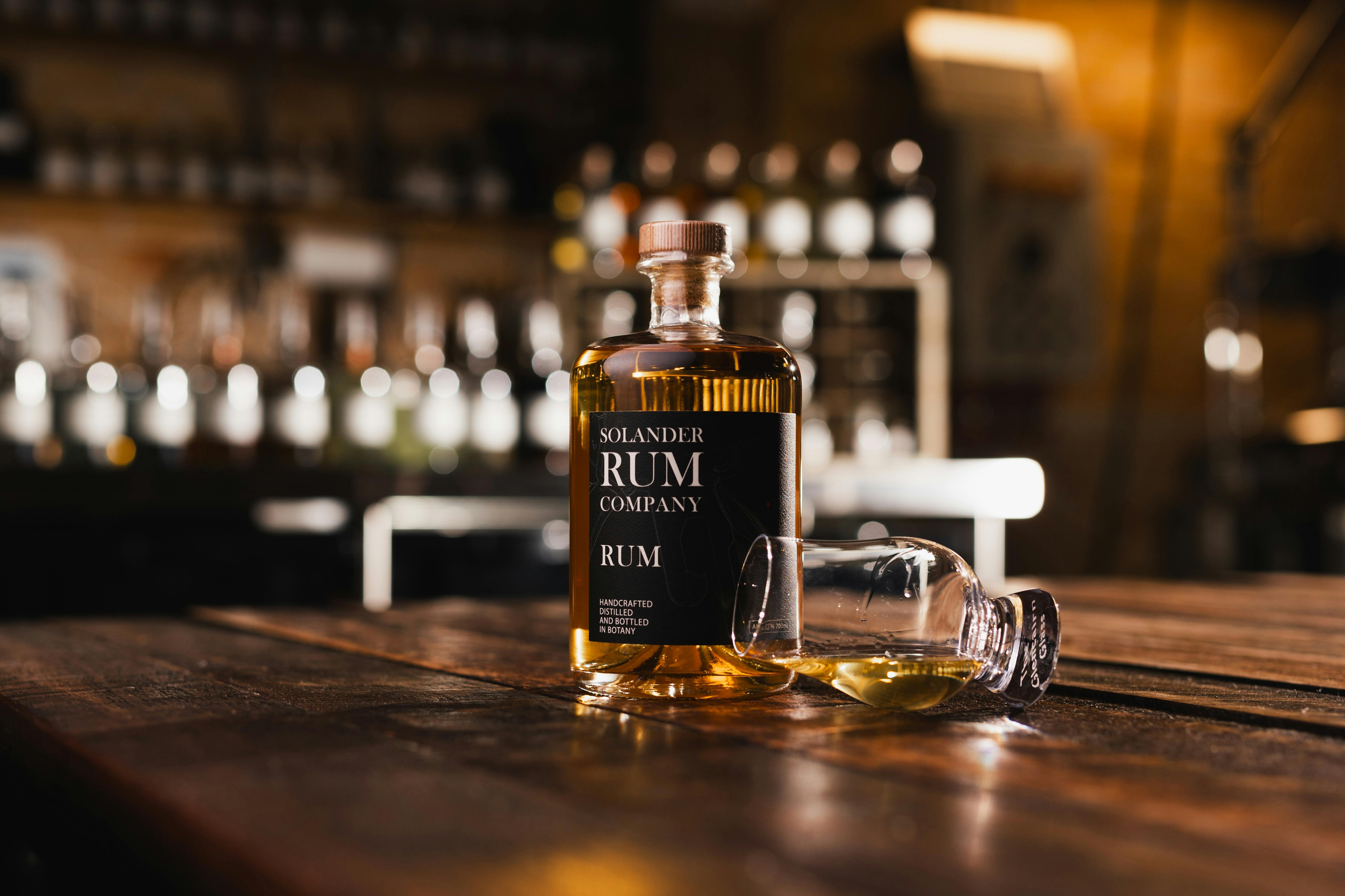 Bottle of Rum on rustic wooden table with a glencairn glass
