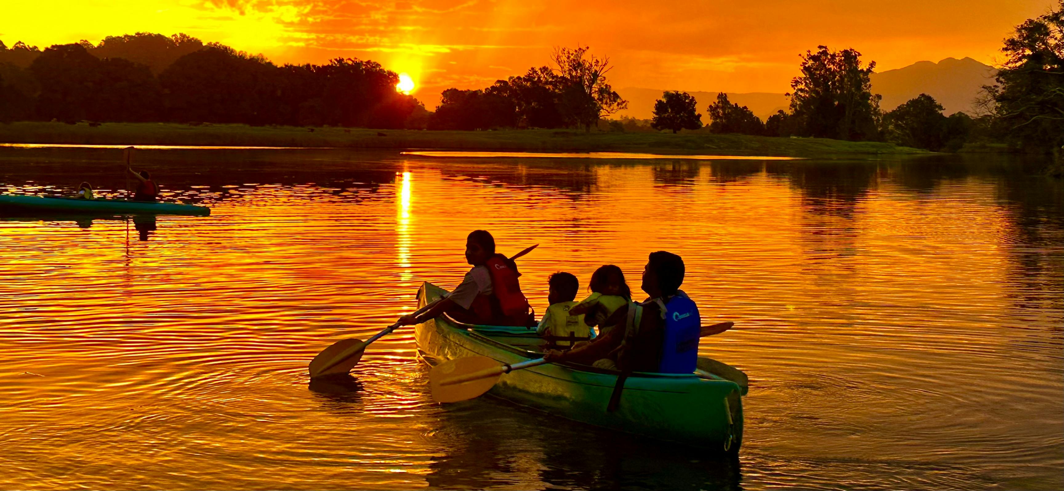 2 adults and 2 children paddling towards a fiery golden sunset with Bellingen Canoe Adventures
