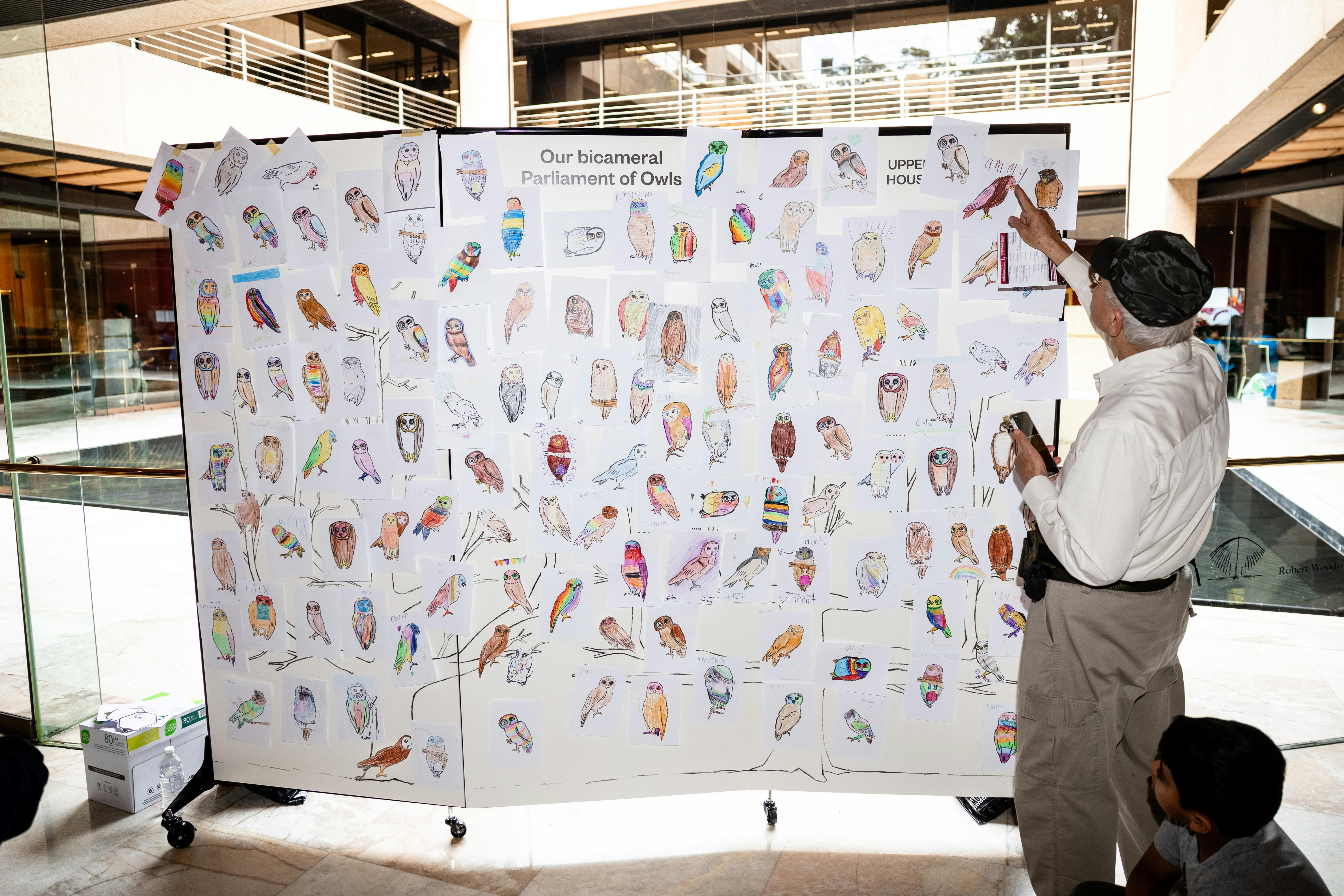 Lots of coloured in pictures of owls are displayed at Family Fun Day at Parliament of NSW