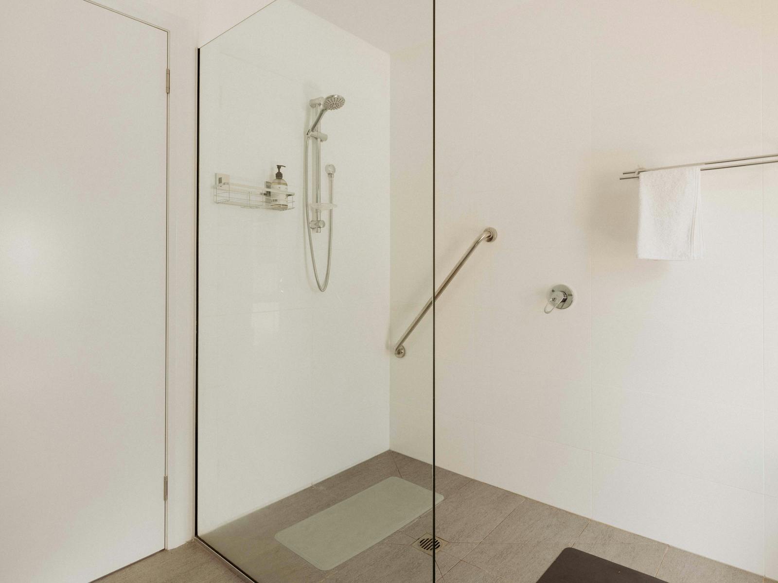 The bathroom features a spacious walk-in shower, toilet, and a convenient washing machine and dryer.