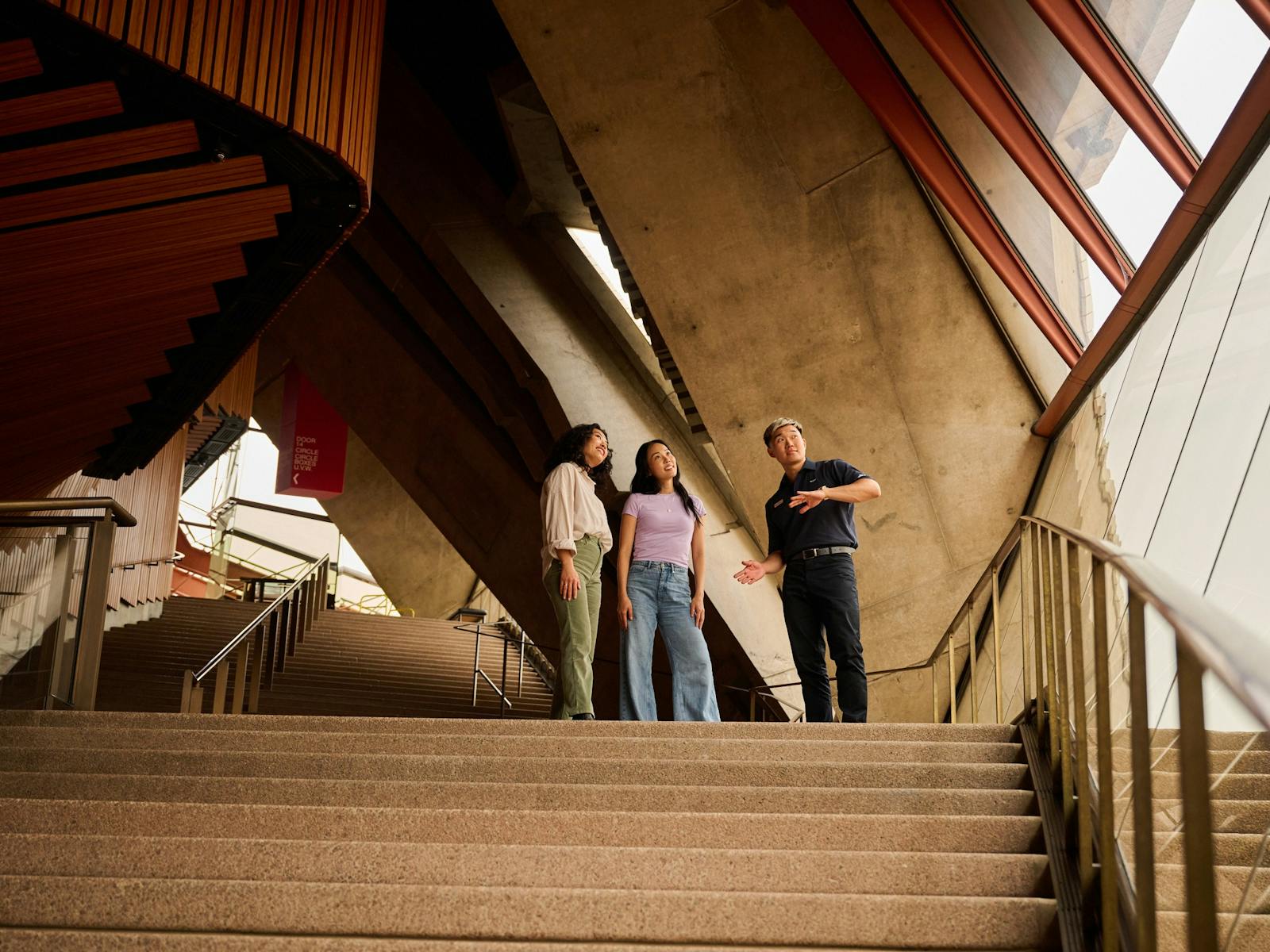 ツアーガイドと階段の上に立って窓の外を眺める2人の女性
