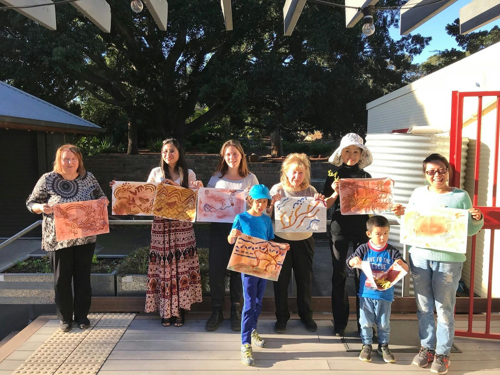 People standing in a line showing their artwork from the Aboriginal Art Workshop