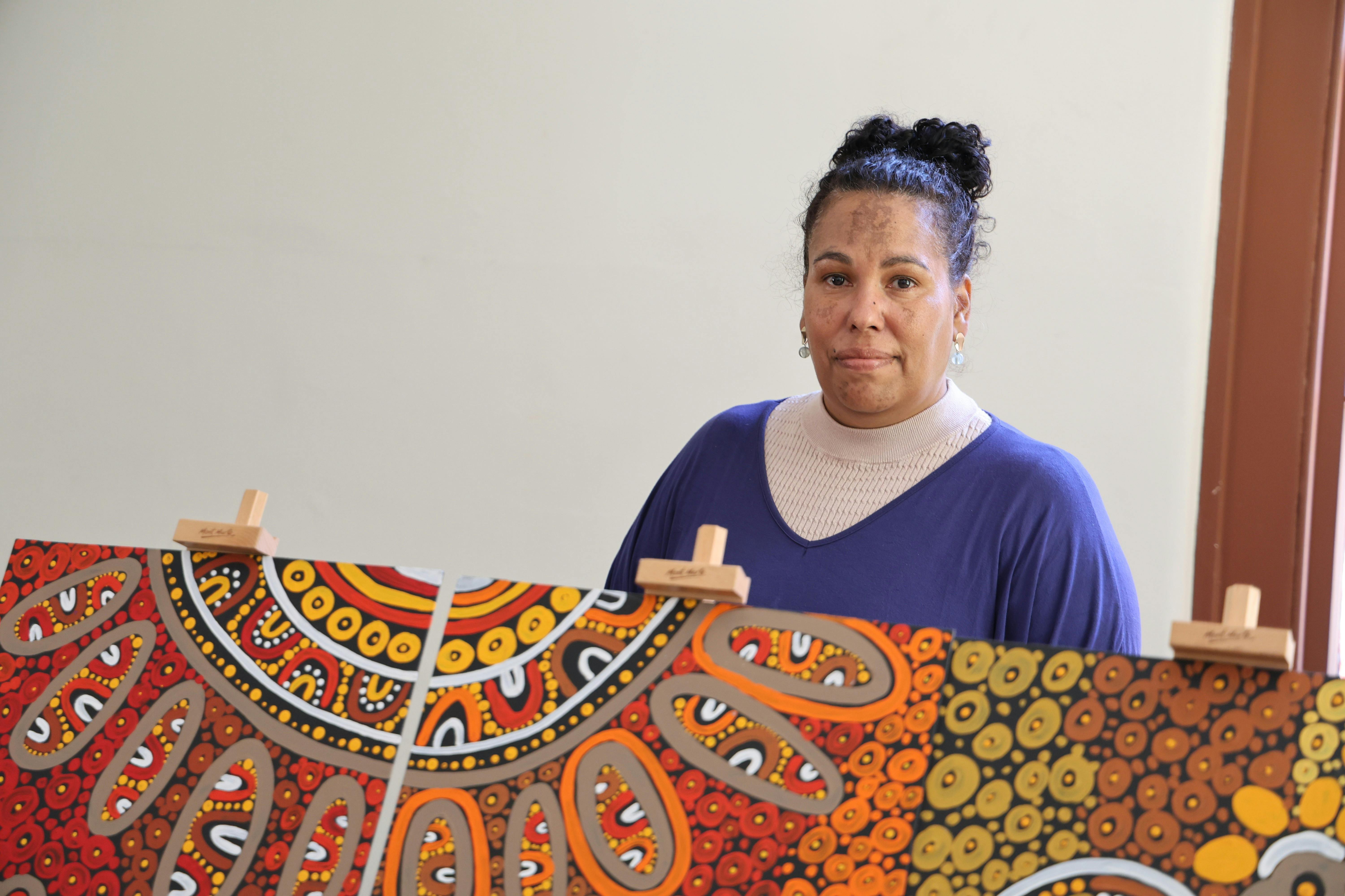 Fiona Reidy holding their aboriginal artwork