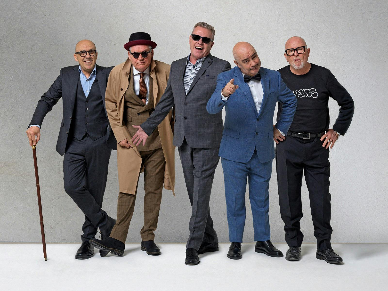 A group of men standing in suits by a white background
