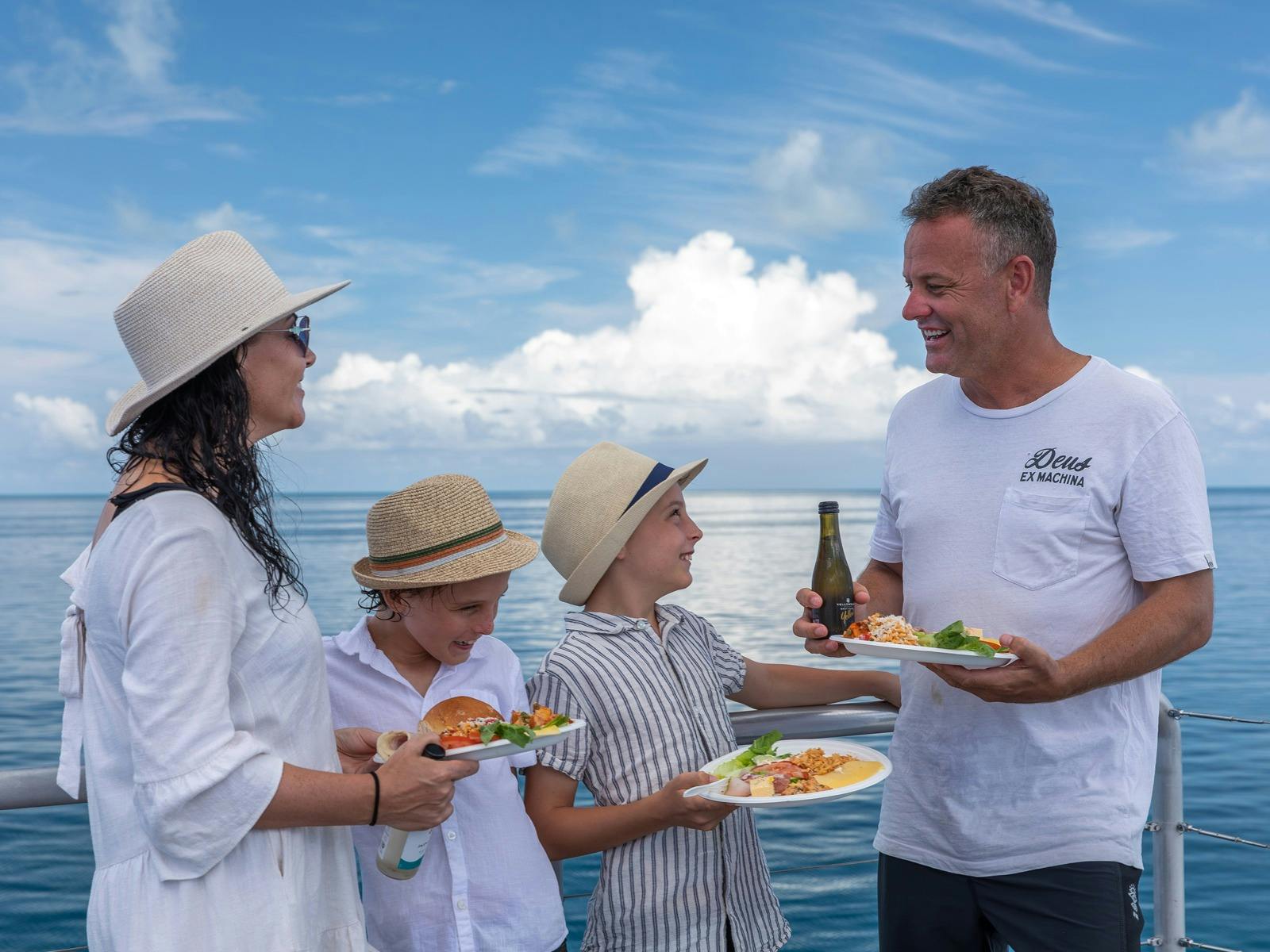 Mum and dad talking to kids on top deck of vessel while eating lunch