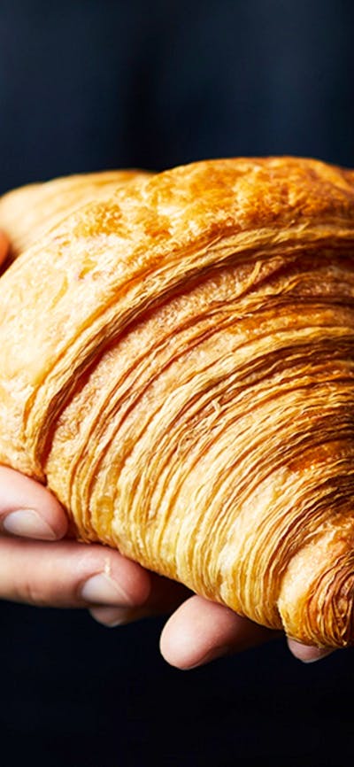 Person wearing black shirt holding a golden croissant