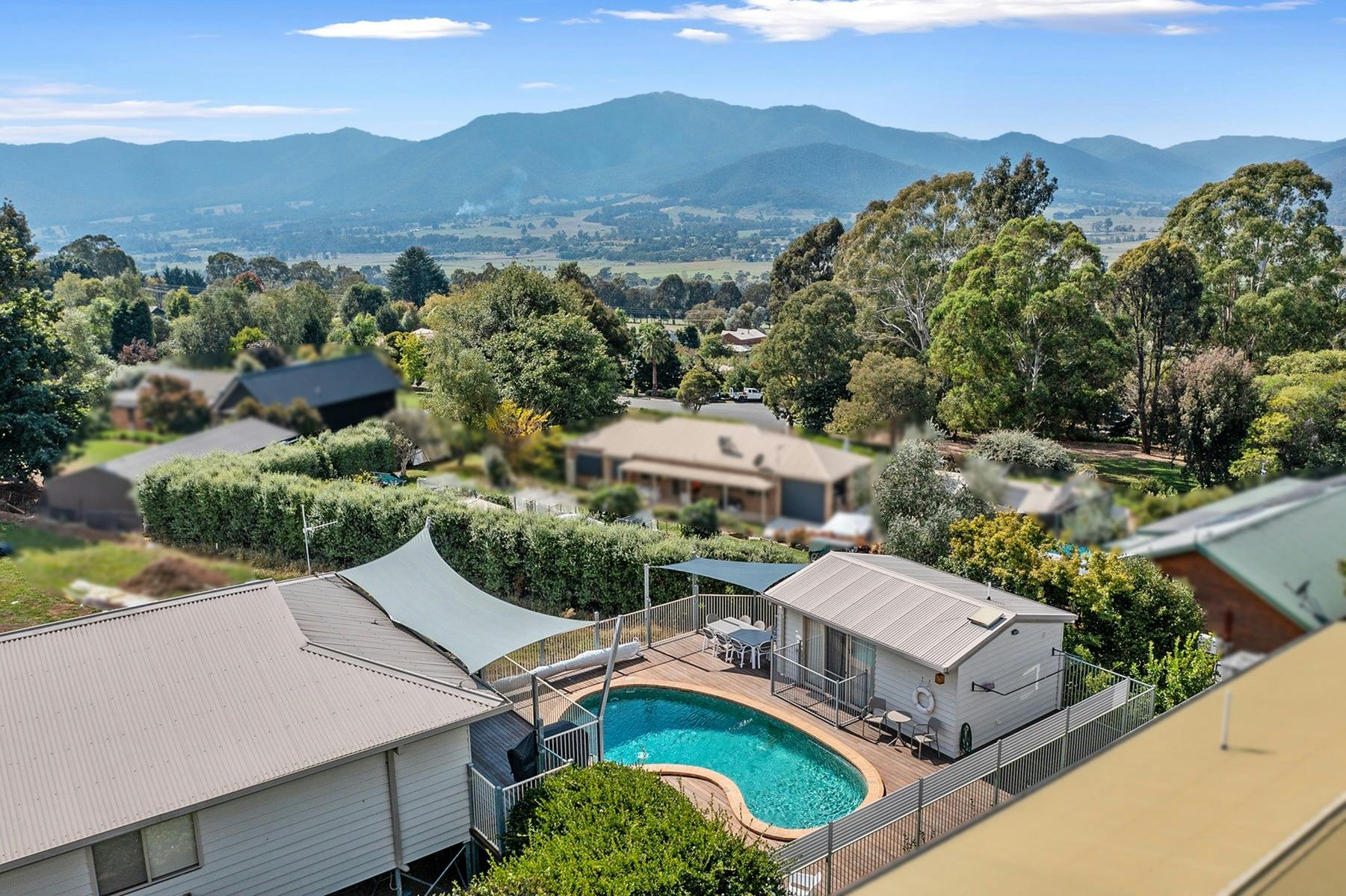 Arial shot of the house with the swimming pool in view and mountains and other houses in the back