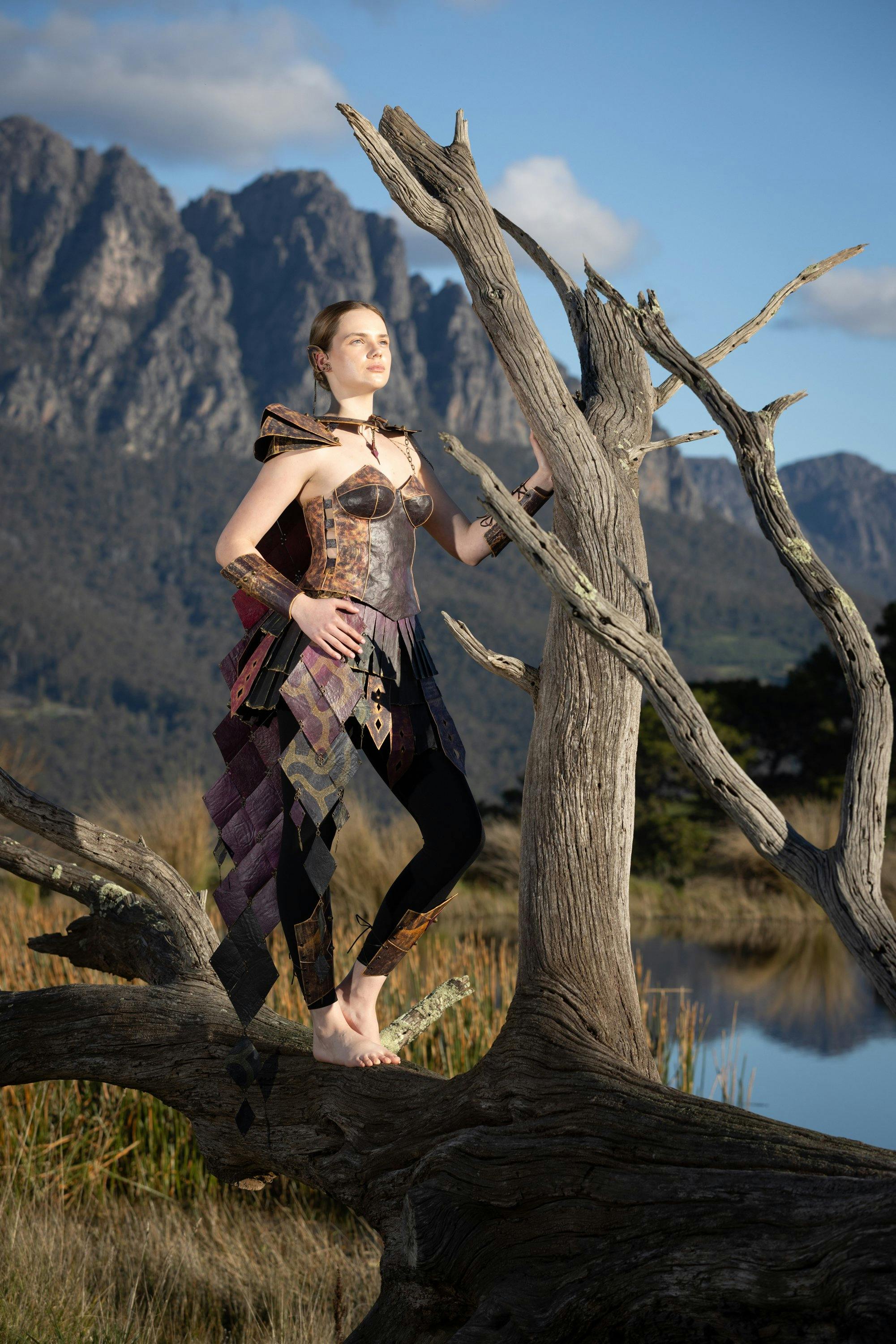 Woman in sci-fi costume stands in a rugged wilderness surveying her land