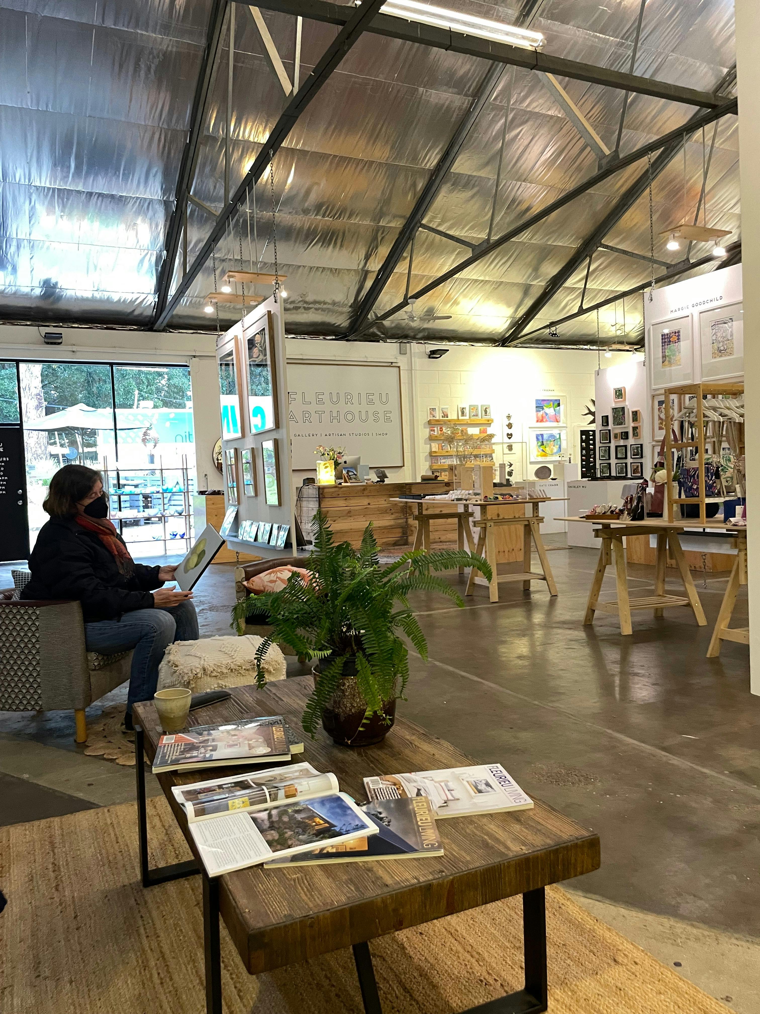 A person sitting on a chair looking at a painting in a retail art gallery store