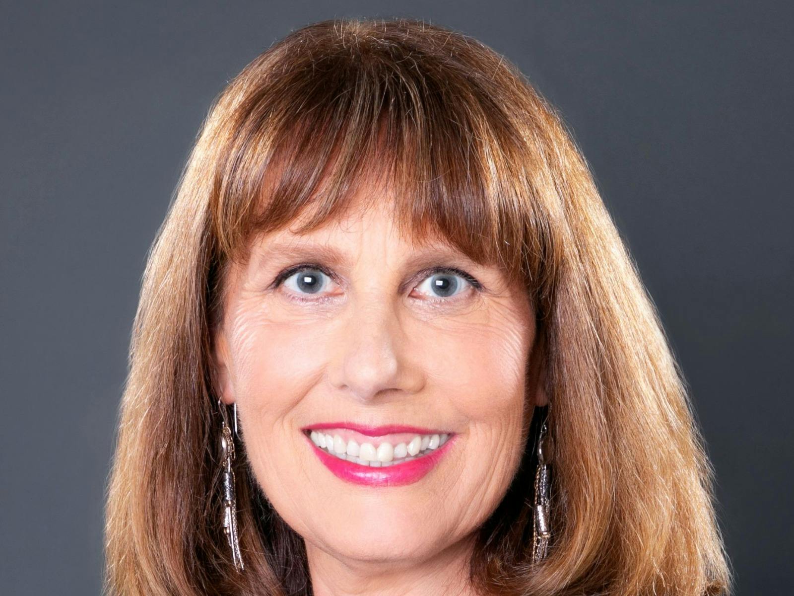 Portrait of a smiling woman with brown hair and long earrings