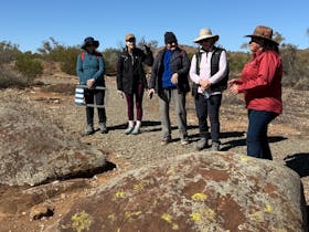 Rehanna talking to a group of women, discussing the petroglyphs that appear ont he rocks