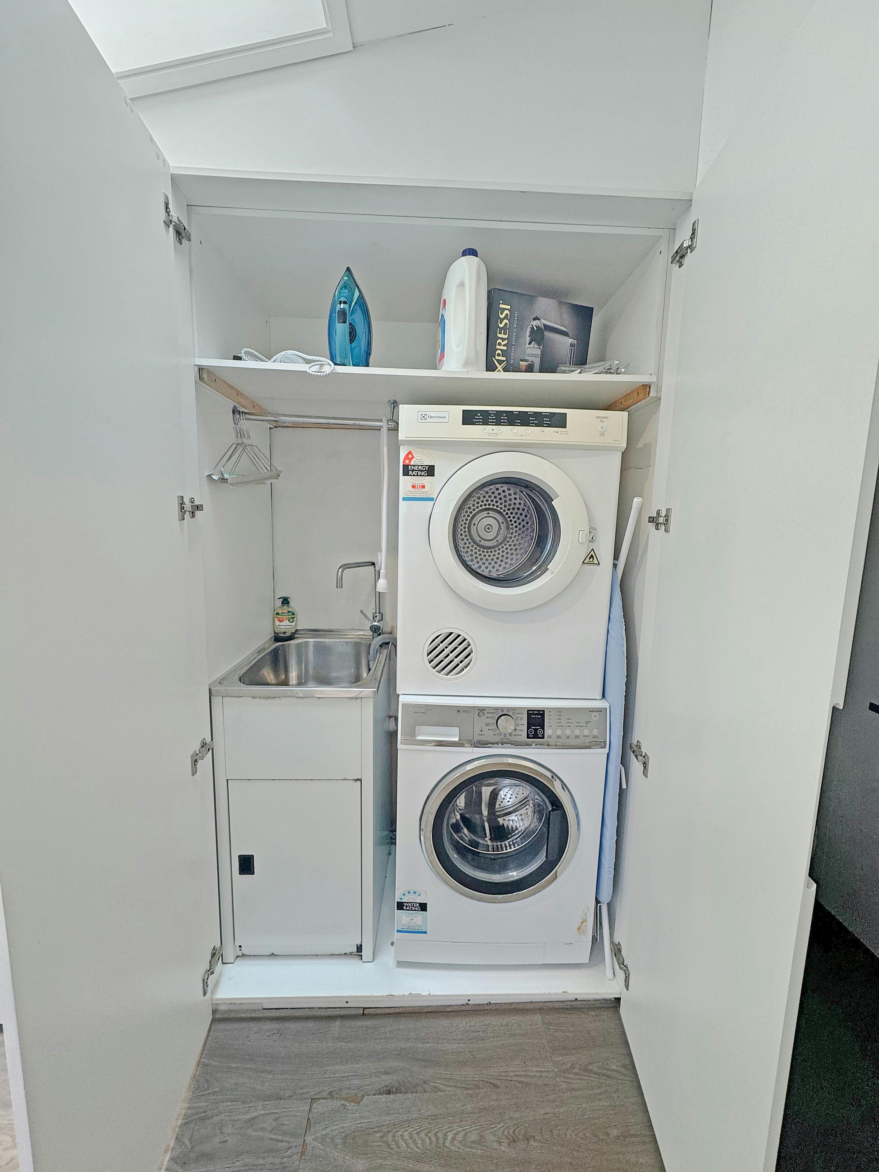 小巧的洗衣區，壁櫥裡有洗衣機、烘乾機和熨斗。