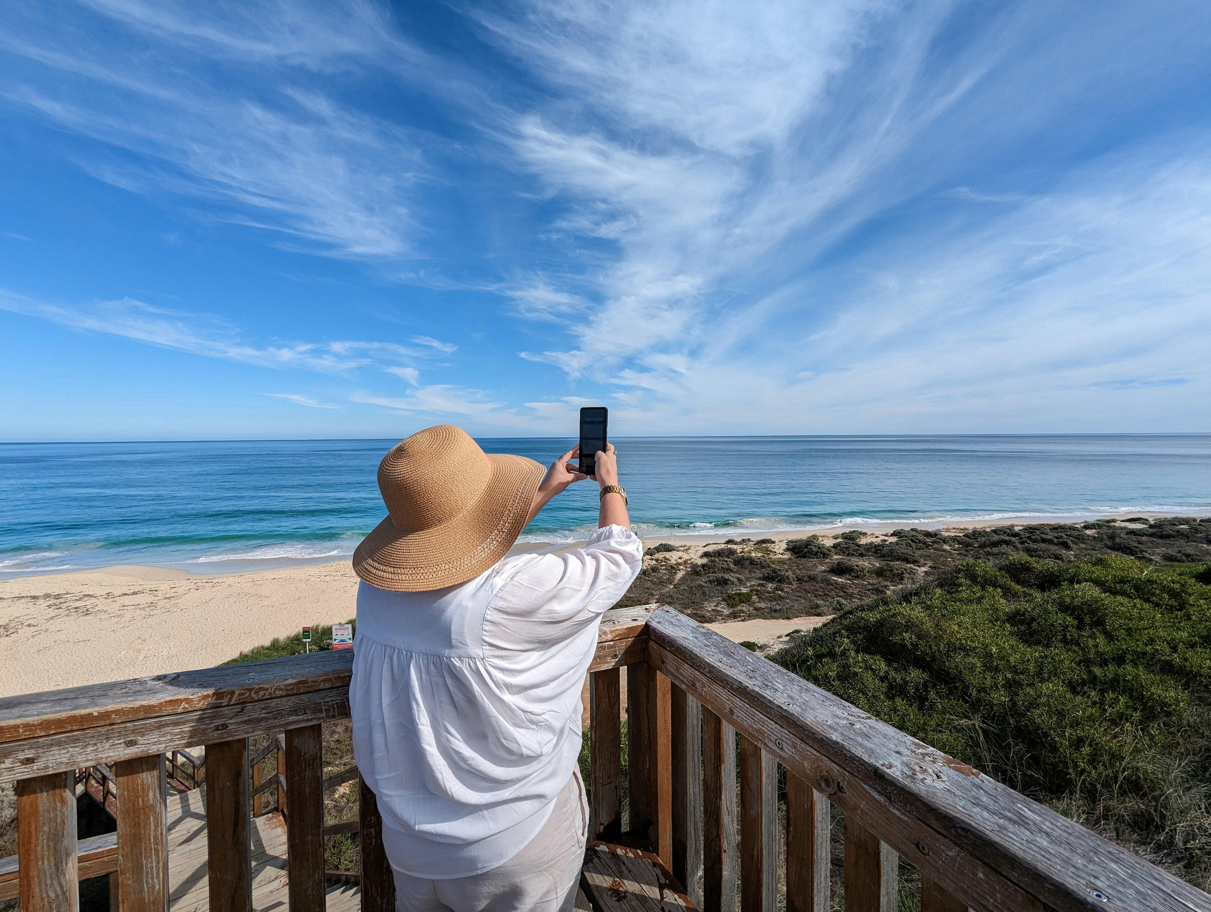 Woman holding a phone using an immersive experience of a sailing ship over the Moore River Mouth