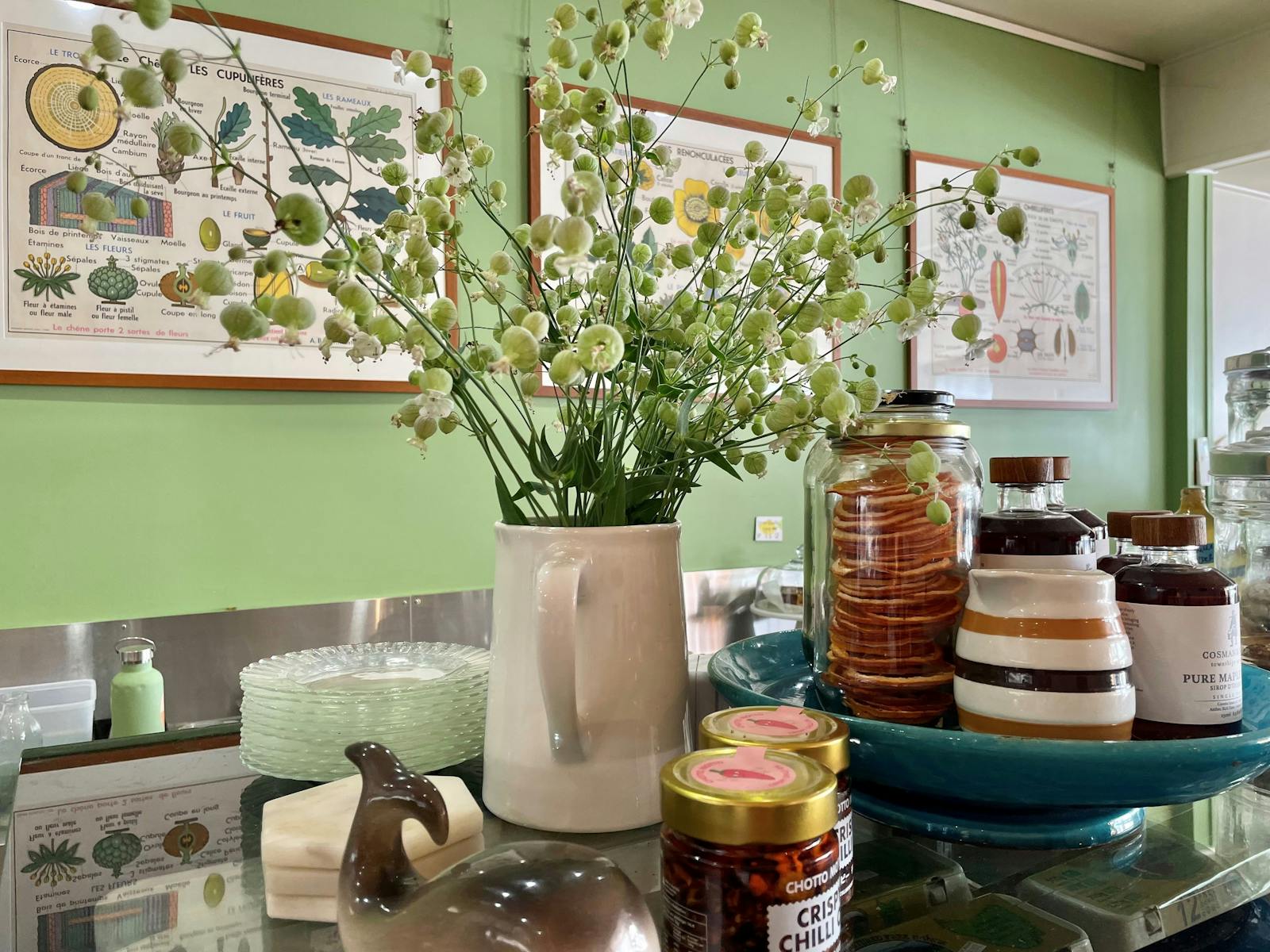 Flowers,maple syrup bottles and chilli jars on counter inside teh cafe