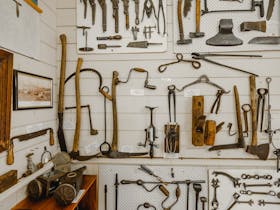 Historic farming tools are hung artfully on a white wall