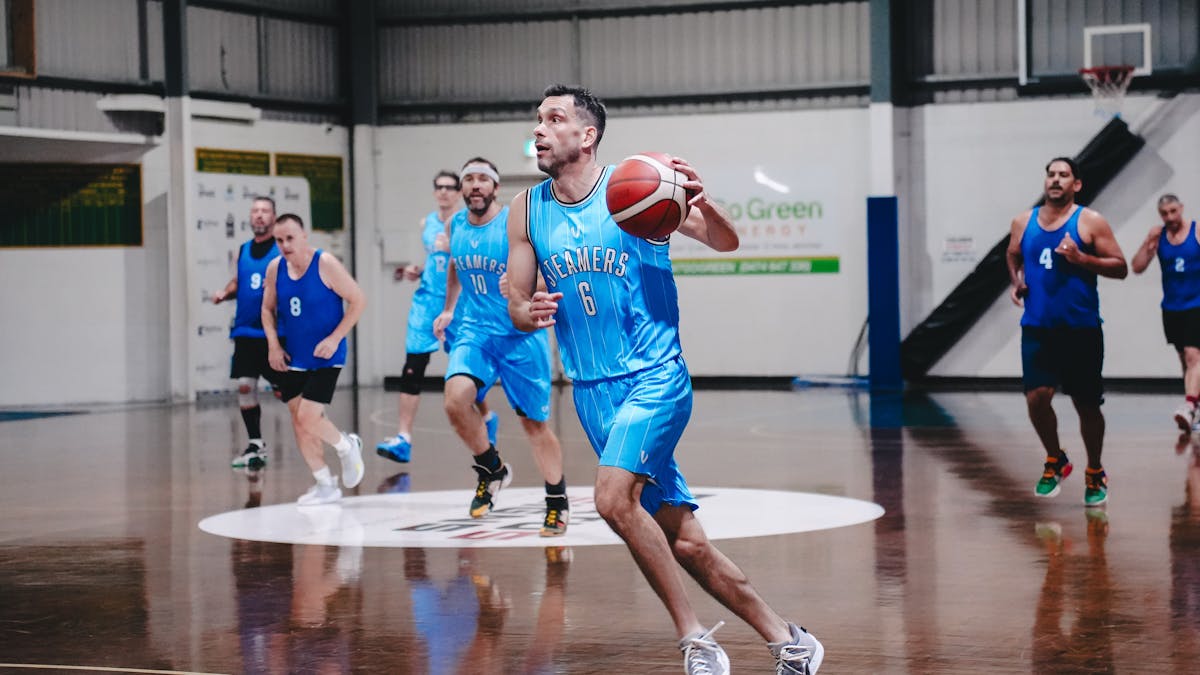 A group of basketball players competes on a court.